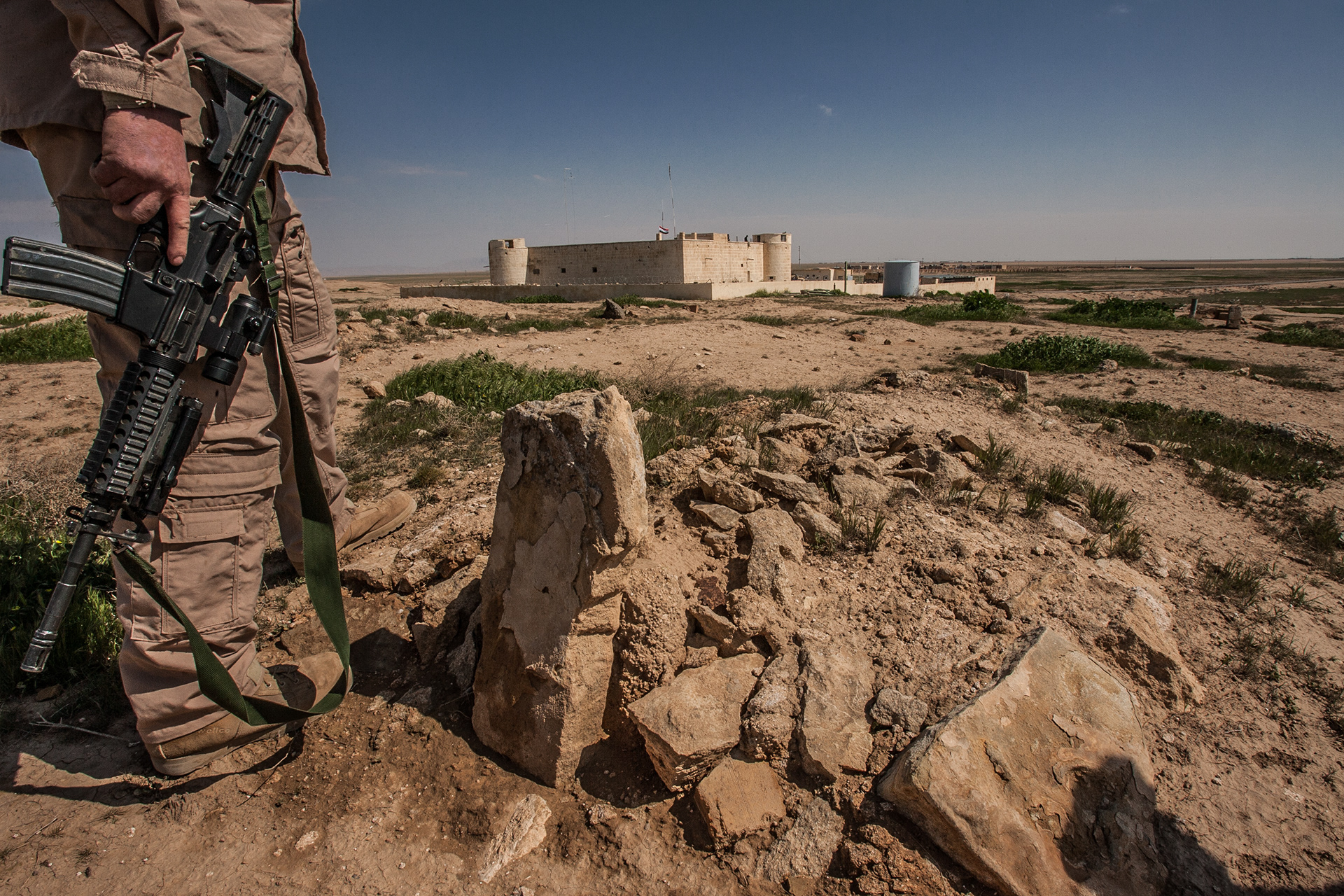 An American soldier looking over a Muslin grave with an Iraqi fort in the background on the Syrian broder.