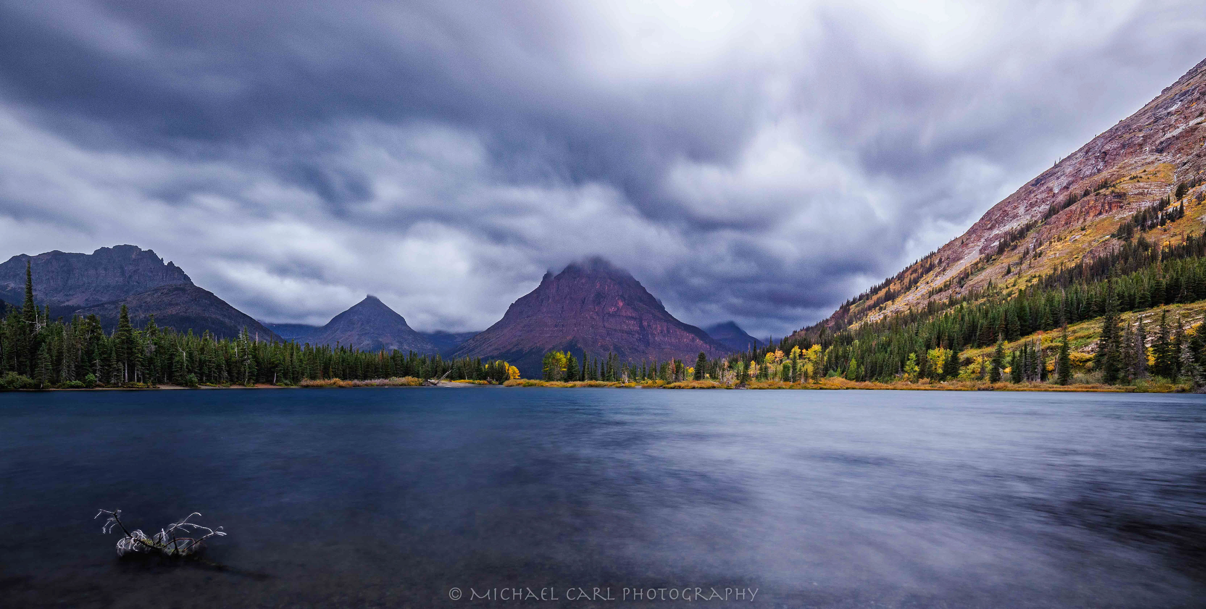 Landscape photography in Glacier National Park as clouds lift over Mount Sinopah along Two Medicine Lake.