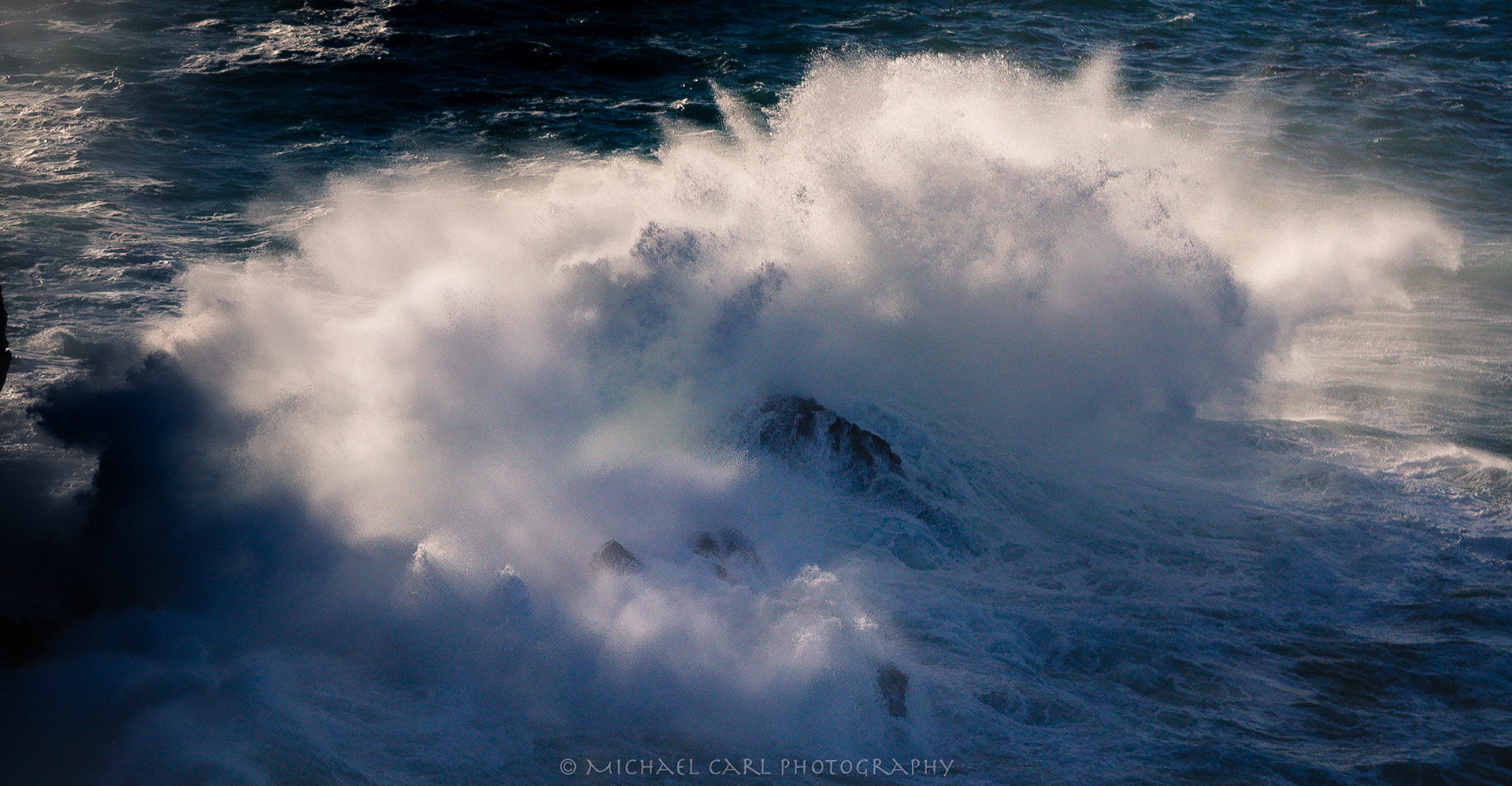 Seascape photography of wave crashing into sea stack along California Coast
