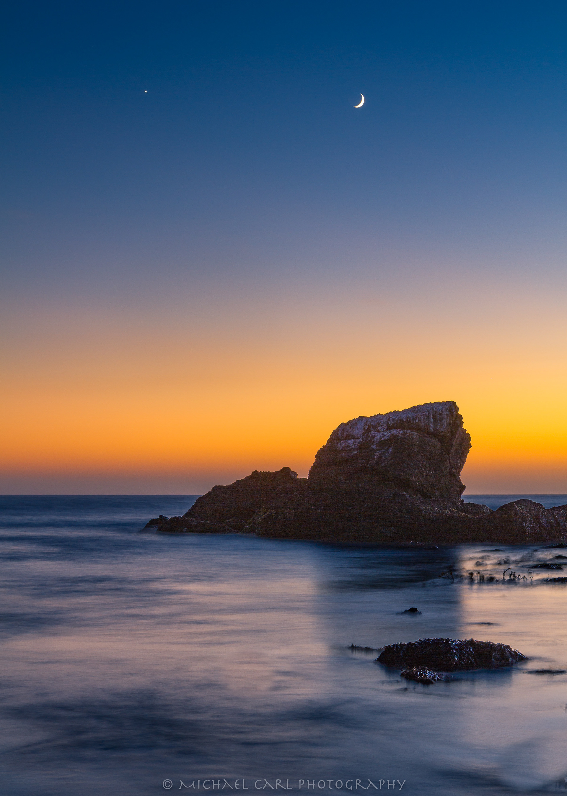 California seascape photography at sunset with quarter moon over sea stack.