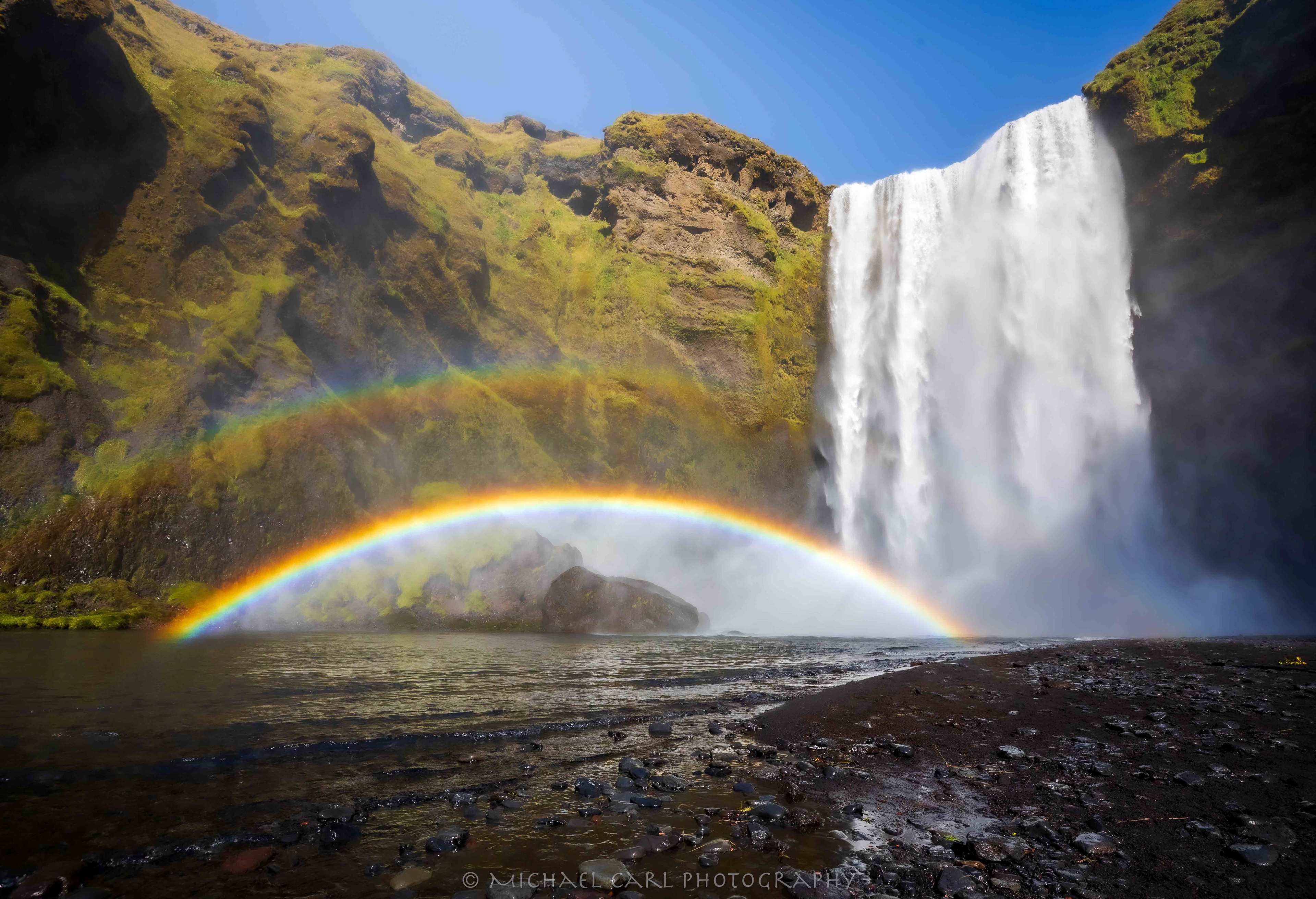 Waterscape photography of double rainbow below Iceland's biggest waterfall Skogafoss.