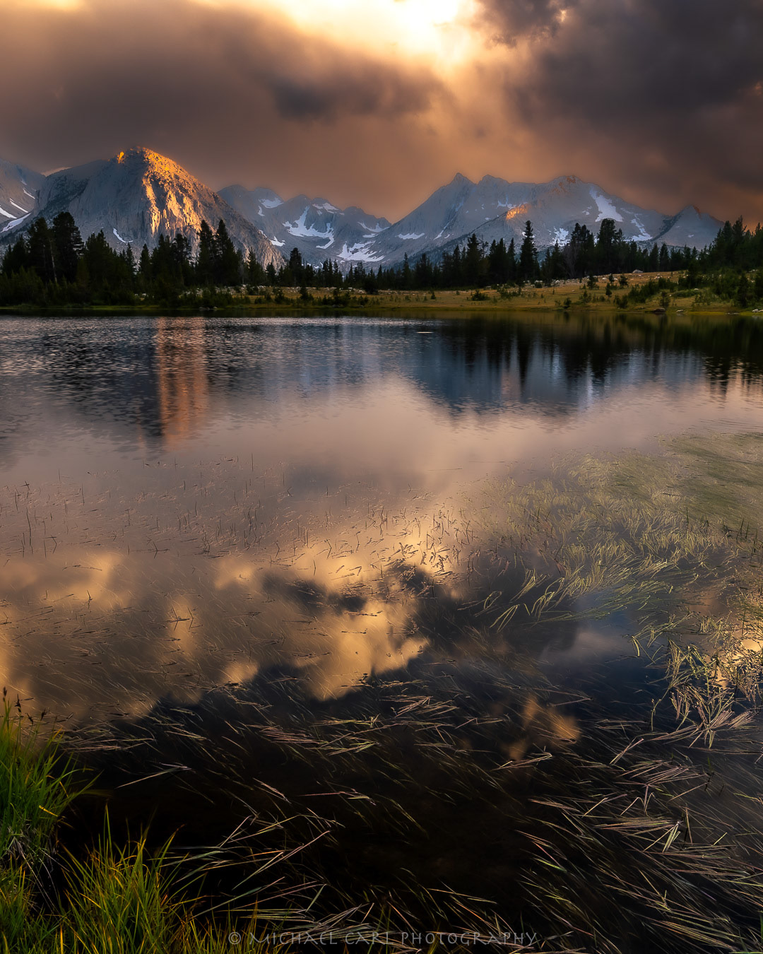 Sierra Nevada Mountains photographed during clearing storm with thunder clouds reflected on lake.