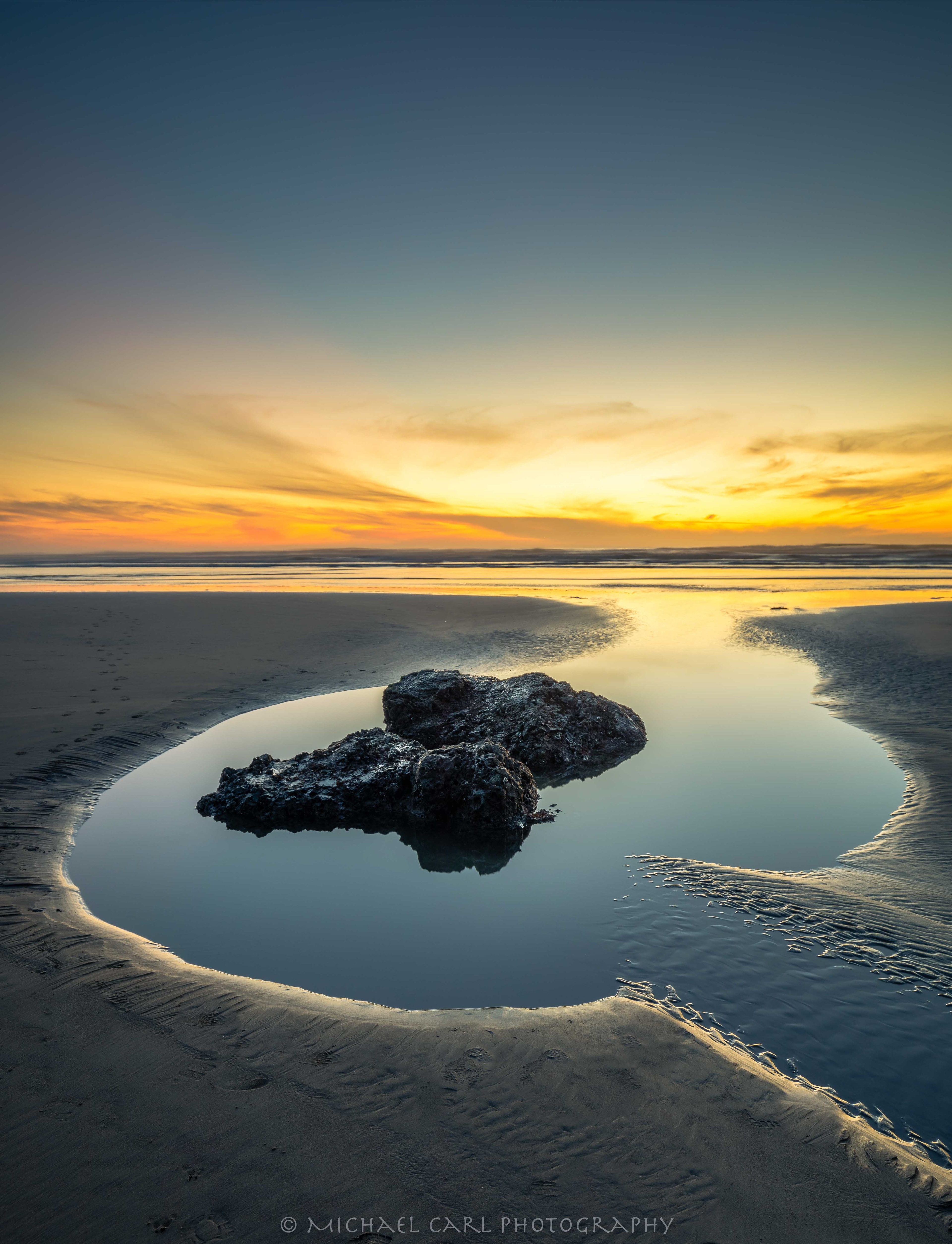 Seascape photography of a tidal pool reflecting the golden light at sunset along the Oregon Coast