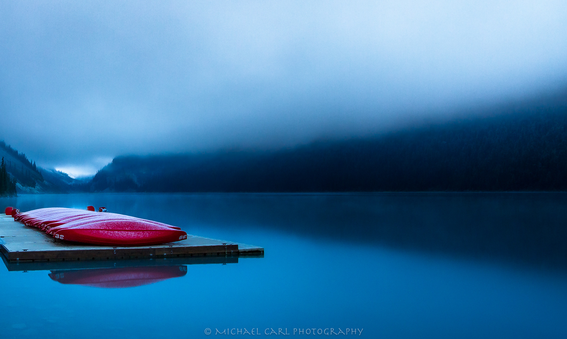 Outdoor adventure photography of snow falling across Lake Louise in Banff National Park.