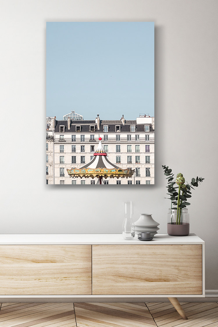 Le manège traditionnel éphémère de la place de l’hôtel de ville à Paris.  Une photographie épurée et originale du chapiteau en cours de démontage du manège. La lumière du milieu de journée révèle les jolies couleurs du carrousel et illumine la facade de l’immeuble parisien.  Localisation : Paris, France.