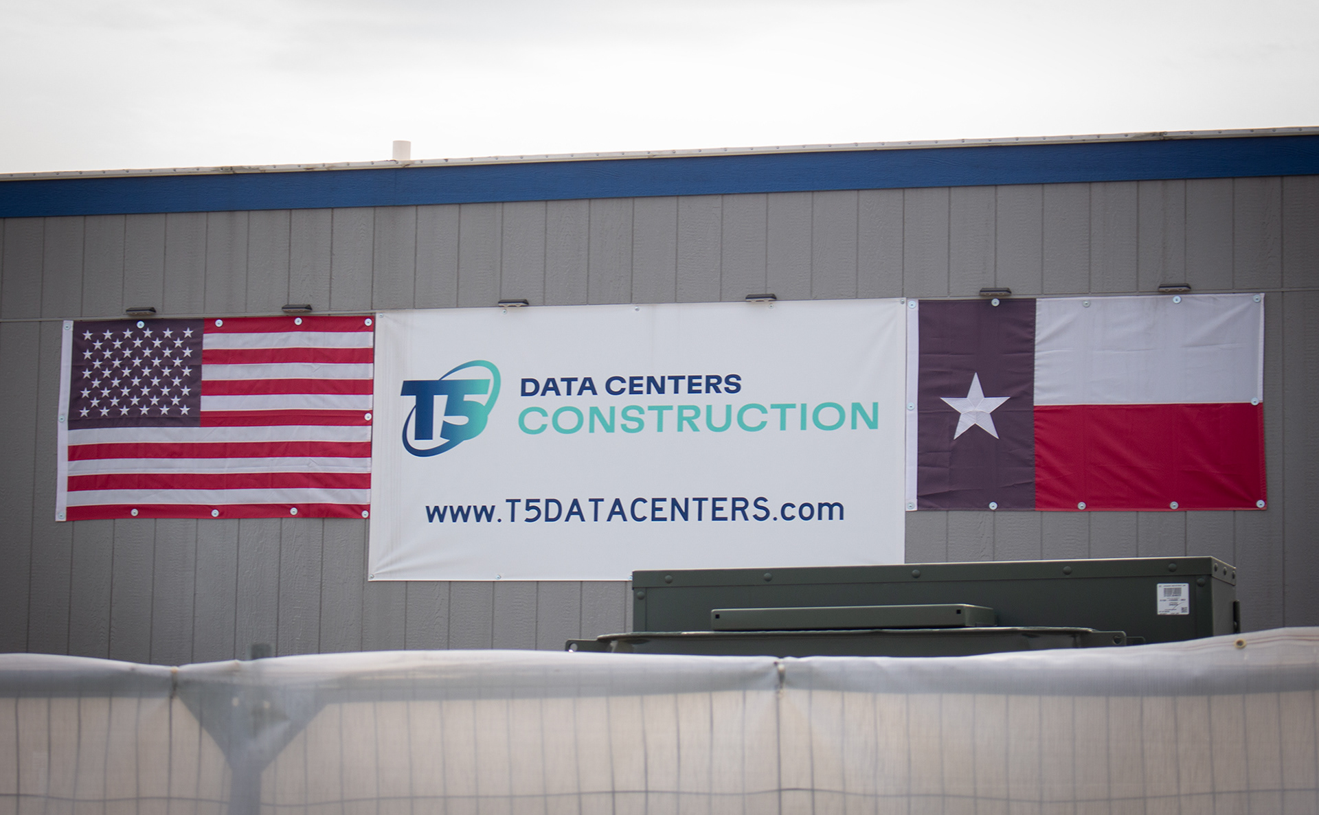 DENTON, TEXAS April 14, 2025  A T5 Data Centers Construction sign, alongside an American and Texas state flag, is posted on the side of a portable trailer on the Core Scientific construction site in Denton, Texas. Photo/ Natalie VanDerWal