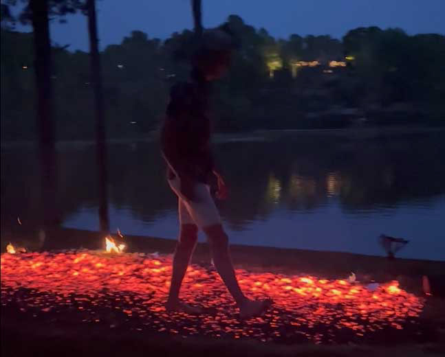 person walking across a glowing bed of embers
