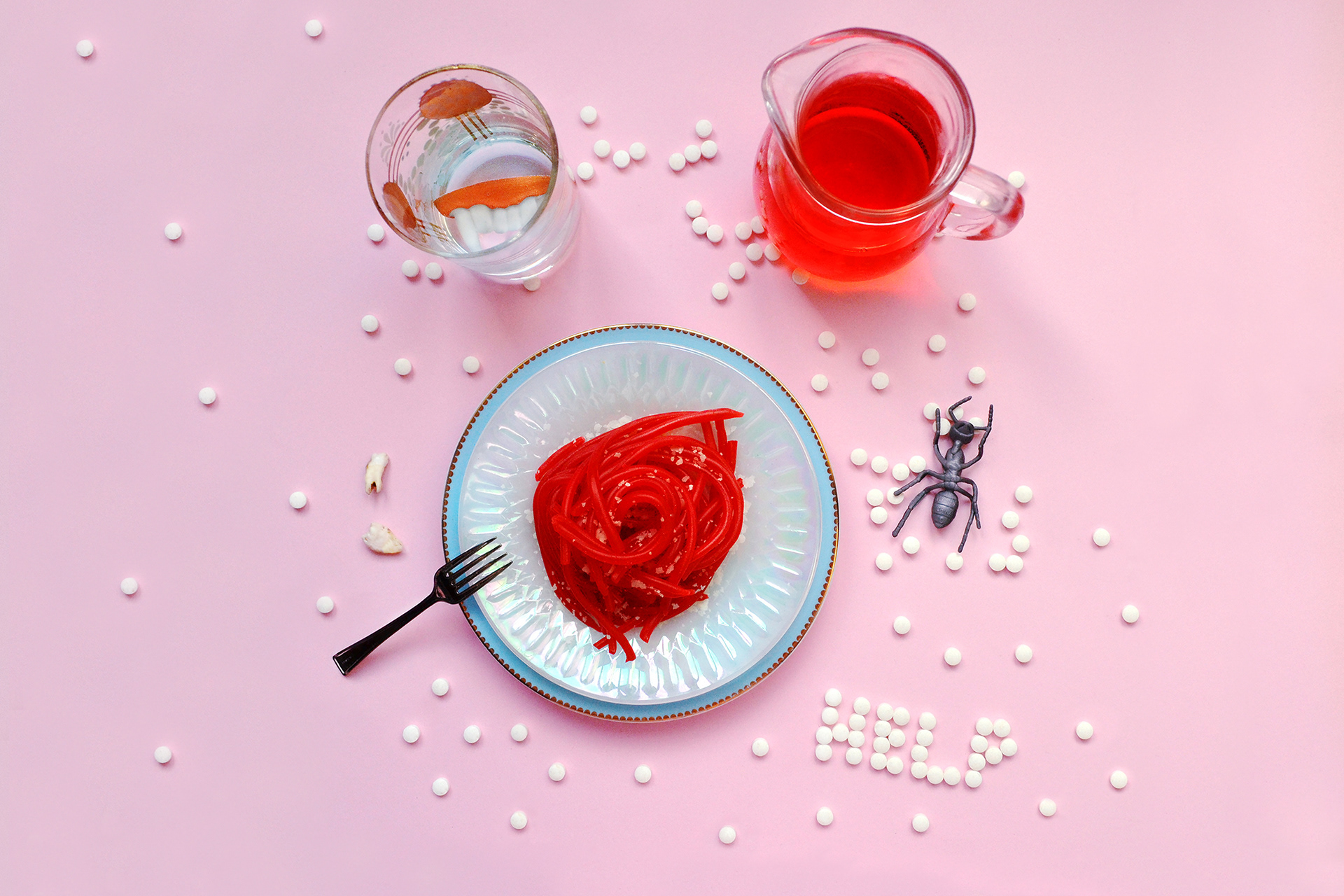 Vampirism – Renfield Syndrome: A glass filled with vampire teeth surrounded by candy-red spaghetti, symbolizing the tension between myth and psychiatric reality.