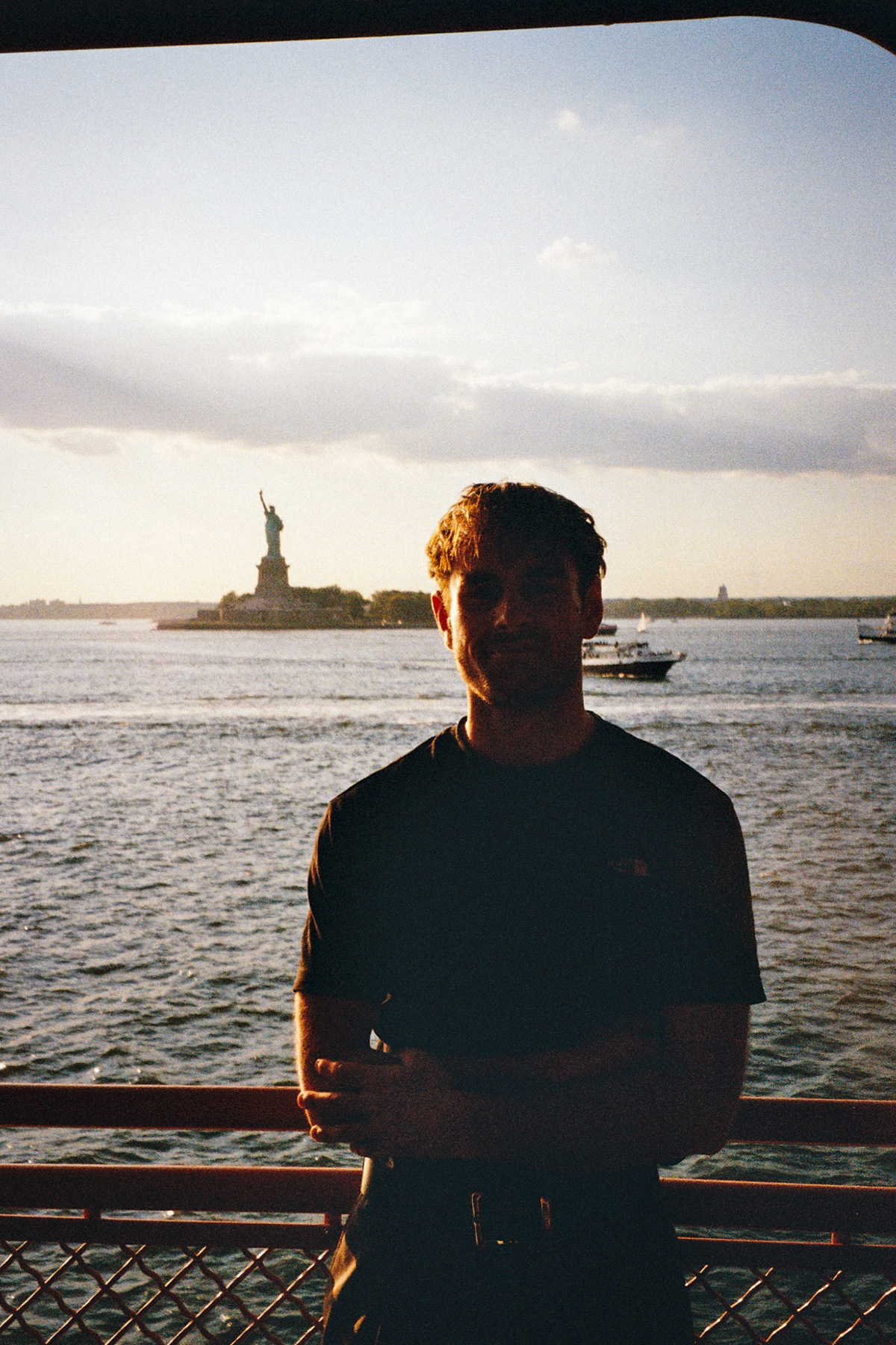 Oscar Johns, photographer and videographer, in New York Harbor with the Statue of Liberty in the background