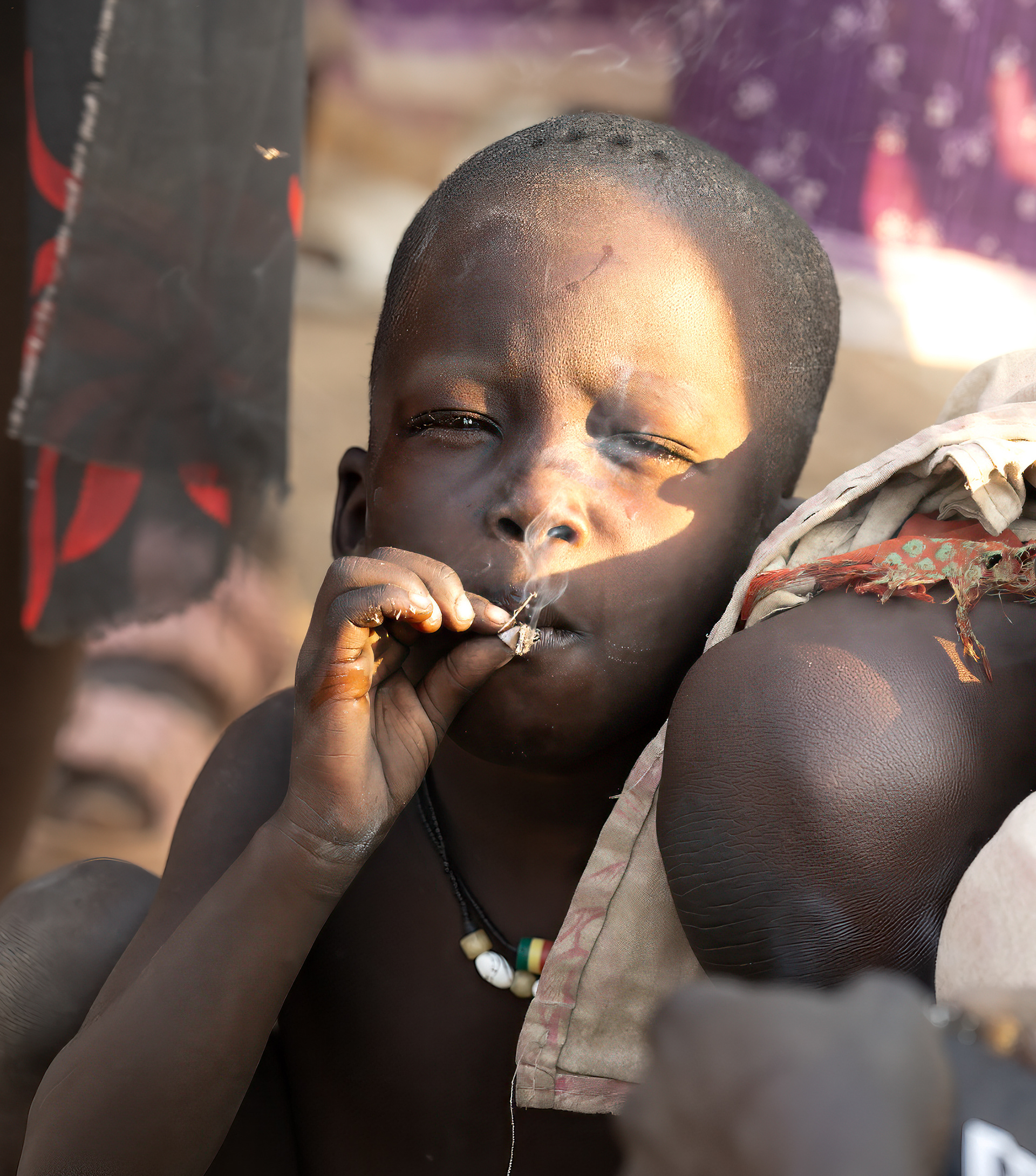 This very young child was crouched at his mother's knee smoking. 