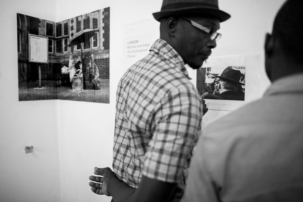 Picture of the frames on the exhibition wall with the caption and also Gallery Attendants at "Londres. Detrás y debajo del palacio de buckingam" exhibition space. gallery arte soy in santiago de cuba, cuba. 2015 © Pedro Rodrigues