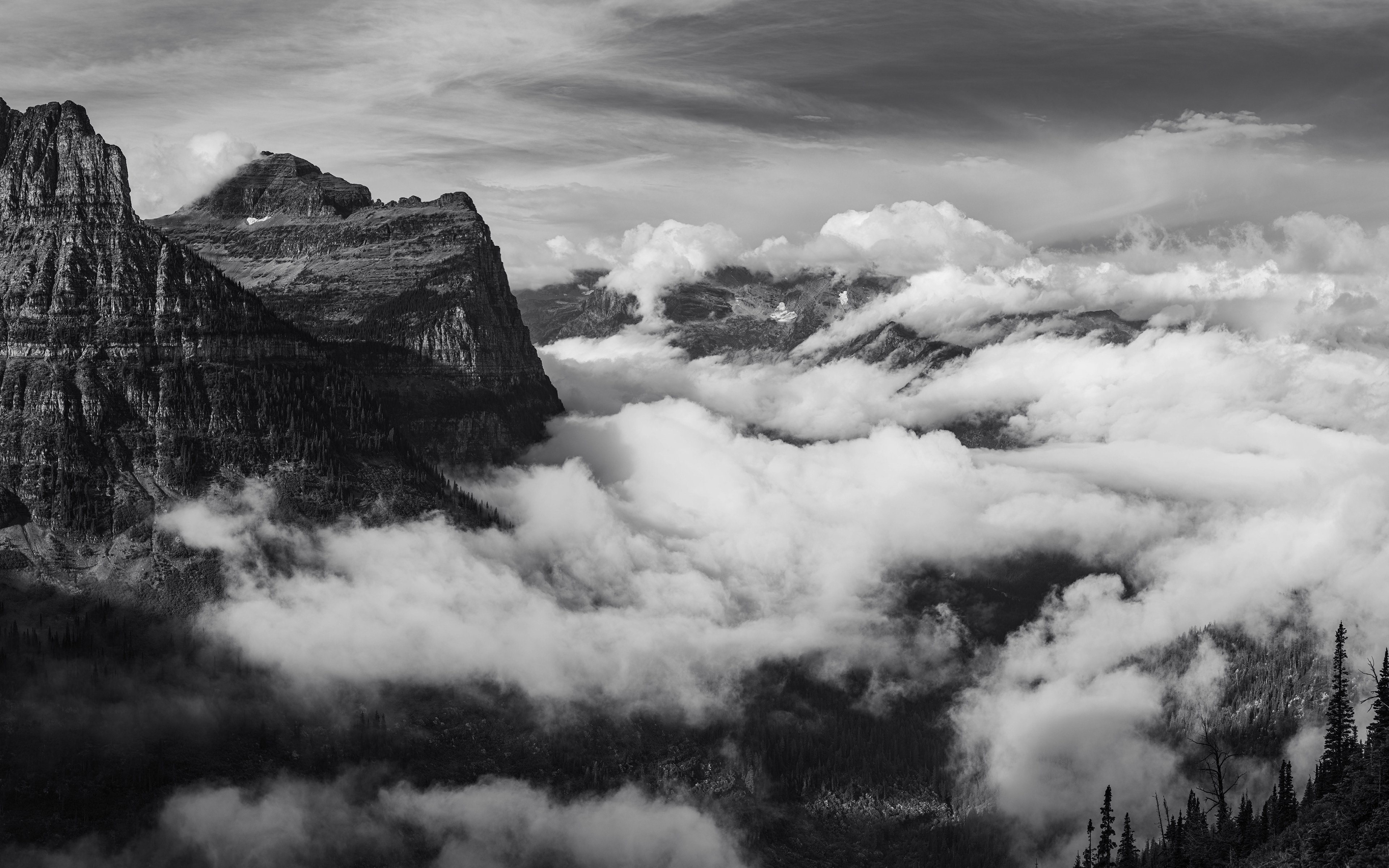 Photograph of Bird Woman Falls and McDonald Creek Valley viewed from Going-to-the-Sun Road in Glacier National Park, Montana, with cascading water, forested slopes, and rugged alpine terrain.