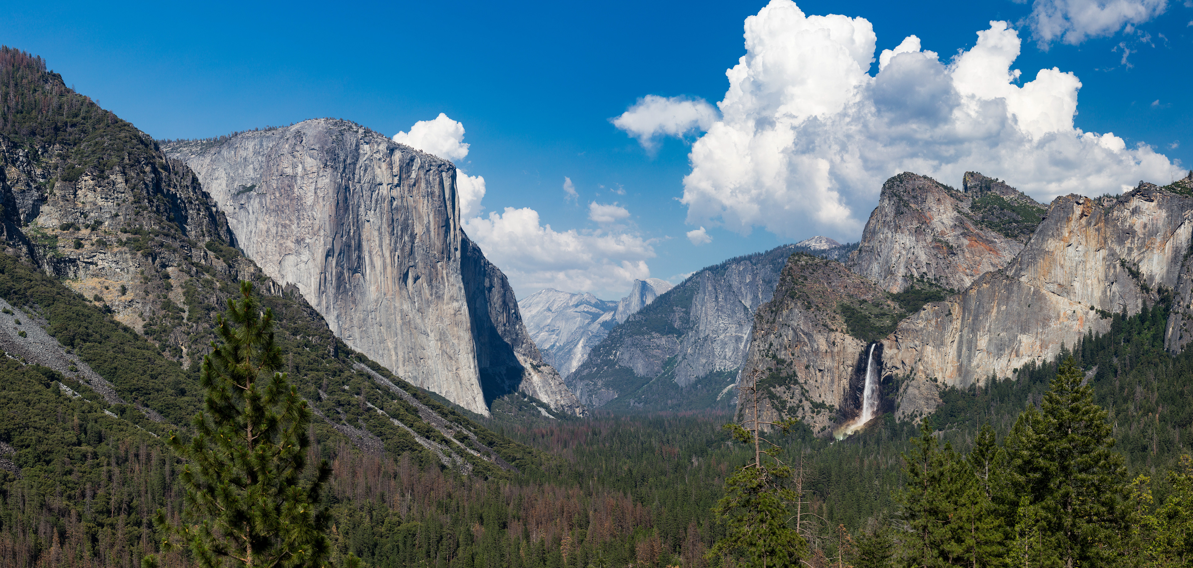 Photograph of Tunnel View in Yosemite National Park, California, featuring El Capitan, Bridalveil Fall, and Yosemite Valley under expansive skies.