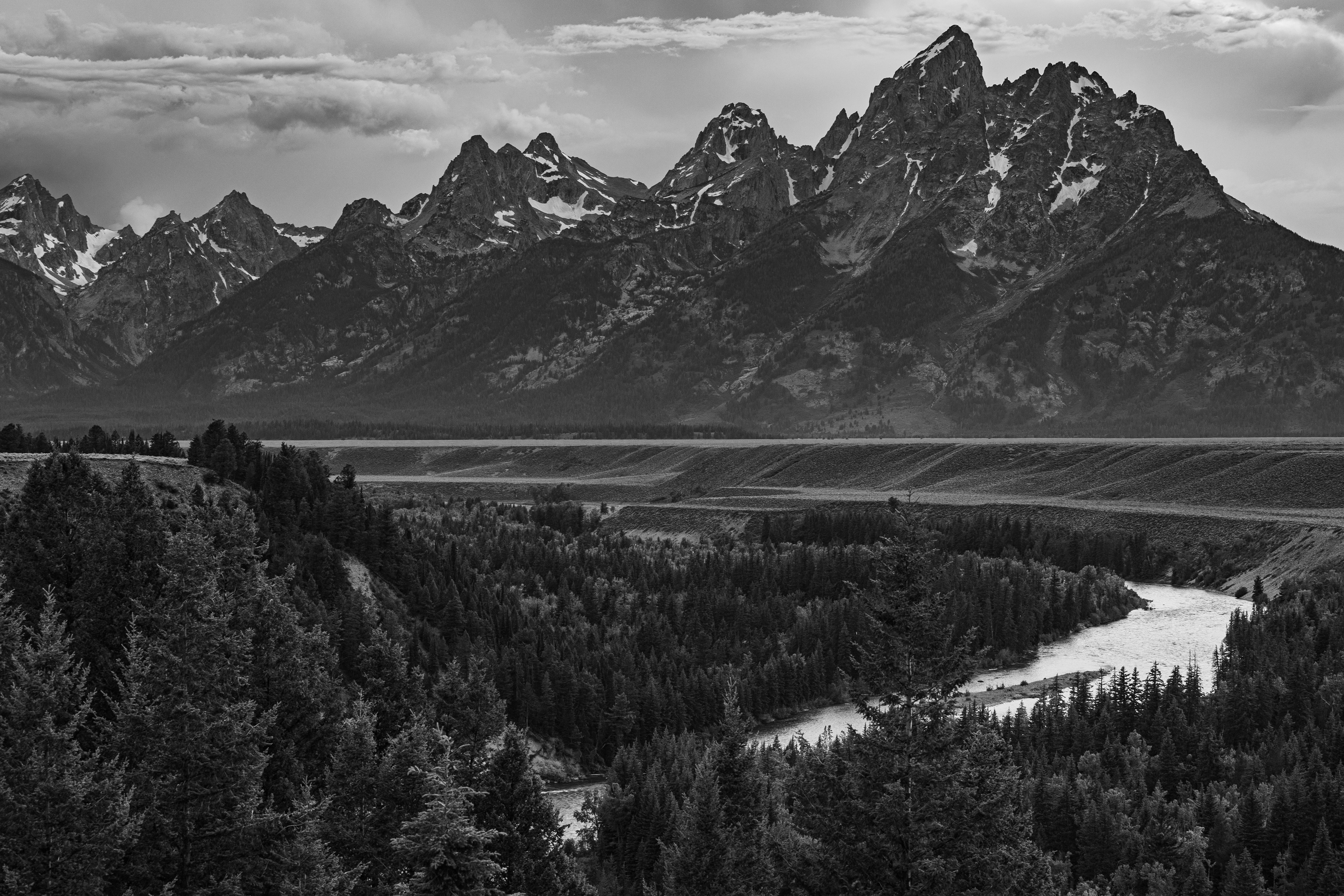 Black and white photograph of the Snake River winding through Grand Teton National Park, Wyoming, with braided river channels, open valley, and the Teton Range rising in the background
