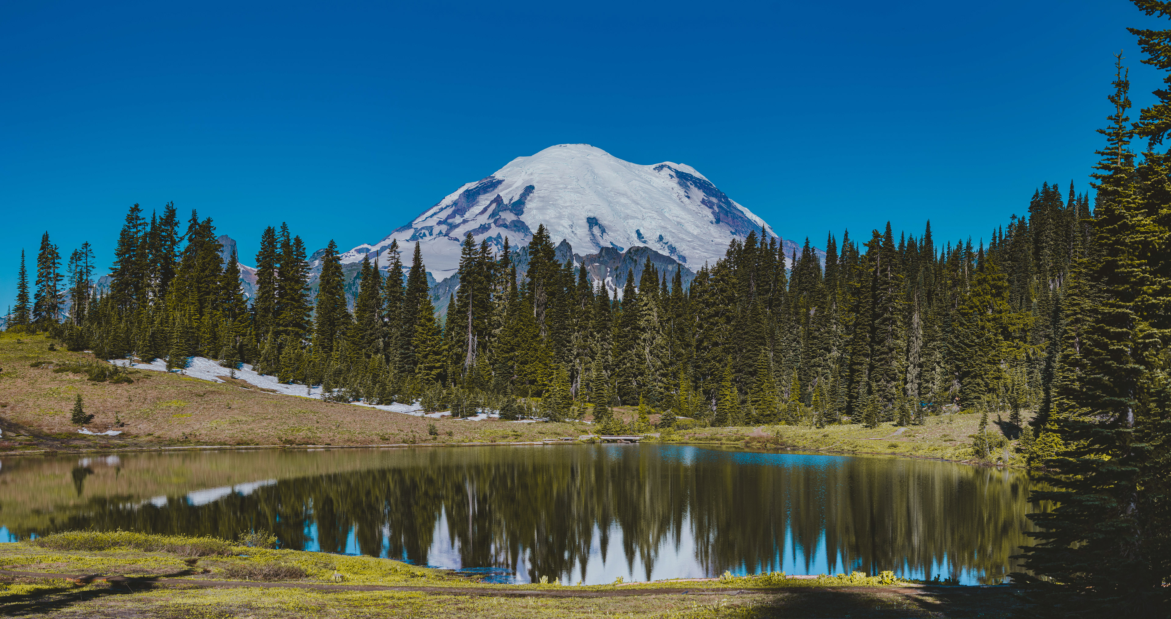 Photograph of Tipsoo Lake with Mount Rainier in Mount Rainier National Park, Washington, featuring an alpine lake, surrounding meadows, and a snow-covered volcanic peak.