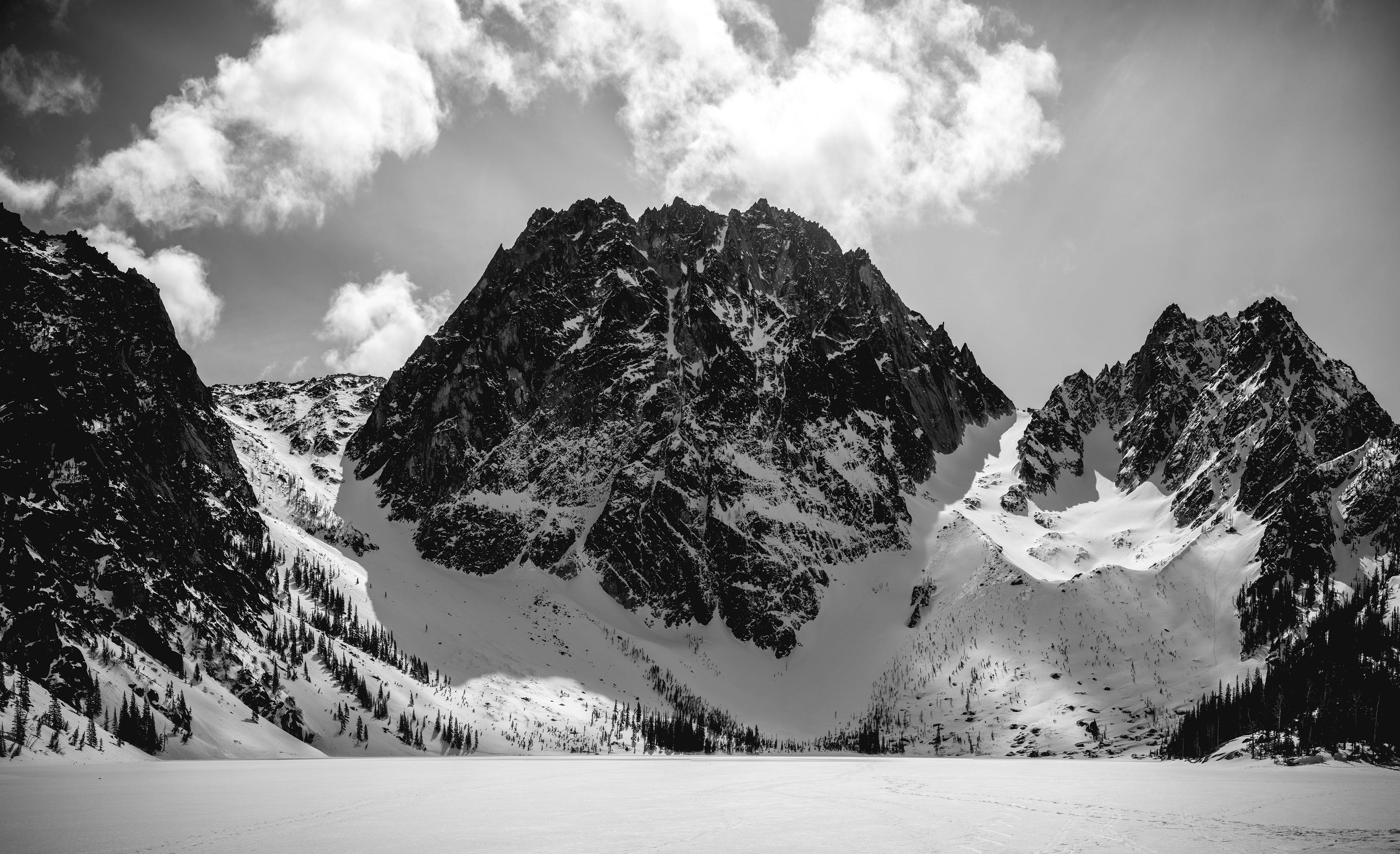 Photograph of Dragontail Peak and Lake Colchuck in winter in the Alpine Lakes Wilderness, Washington, with snow-covered terrain, frozen water, and rugged alpine peaks.