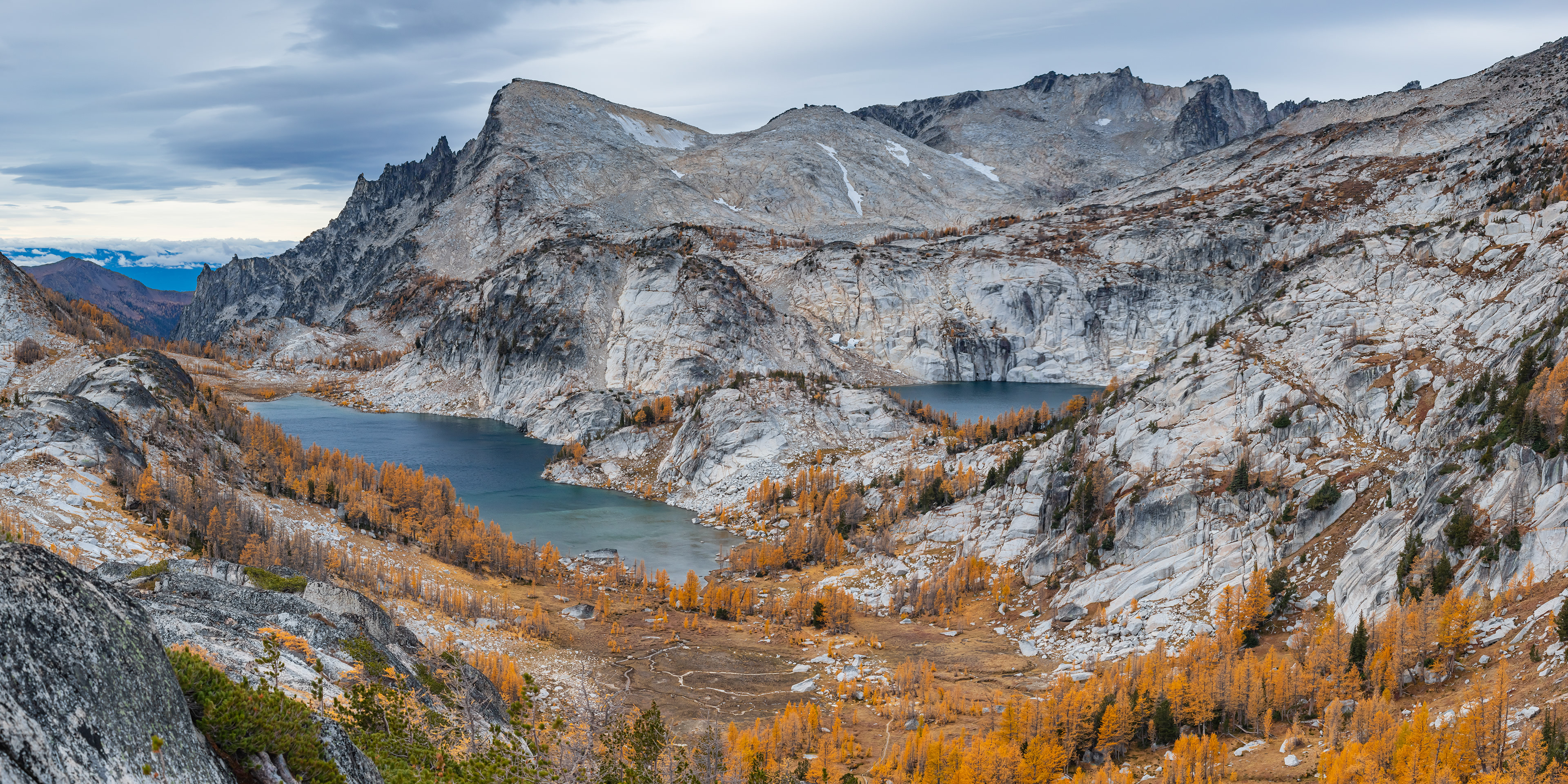 Photograph of Inspiration Lake and Perfection Lake viewed from Prusik Pass in the Enchantments, with golden fall larch trees, granite peaks, and clear alpine lakes in the Alpine Lakes Wilderness, Washington