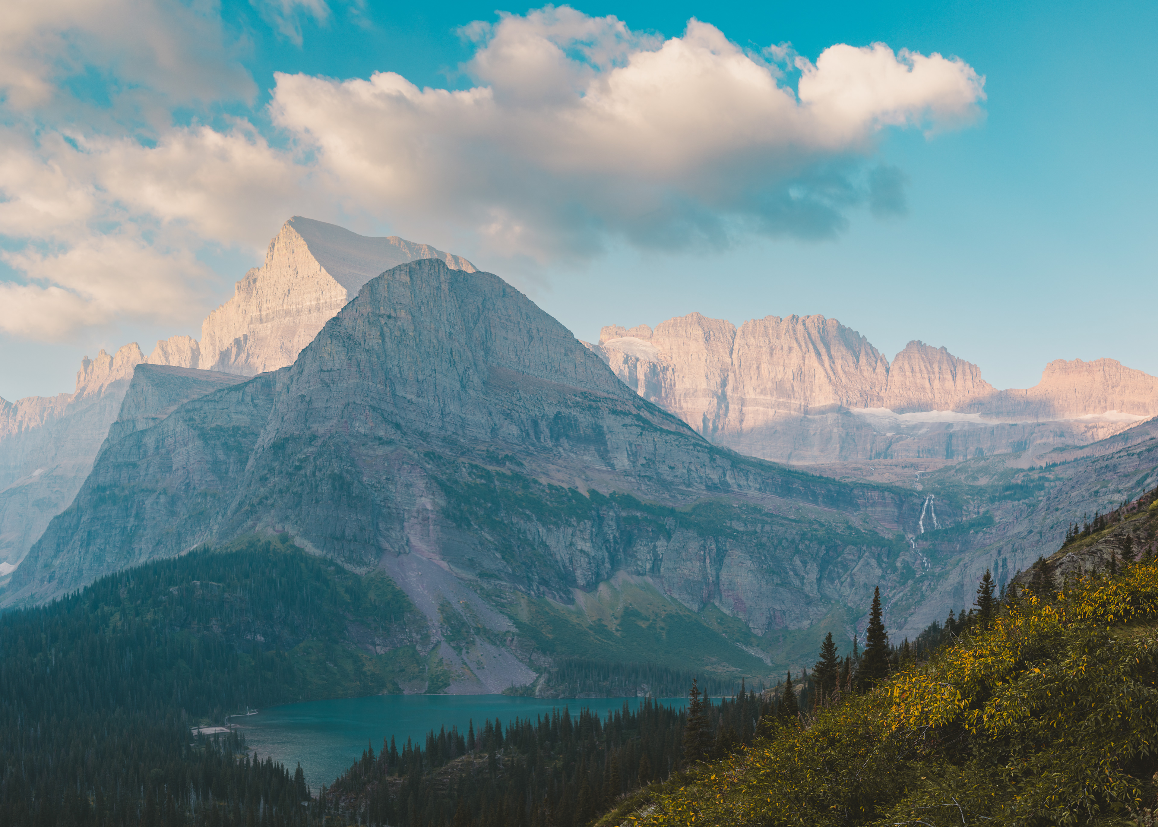 Landscape photograph of Grinnell Lake and Angel Wing in Glacier National Park, Montana, featuring clear glacial water and dramatic alpine peaks.