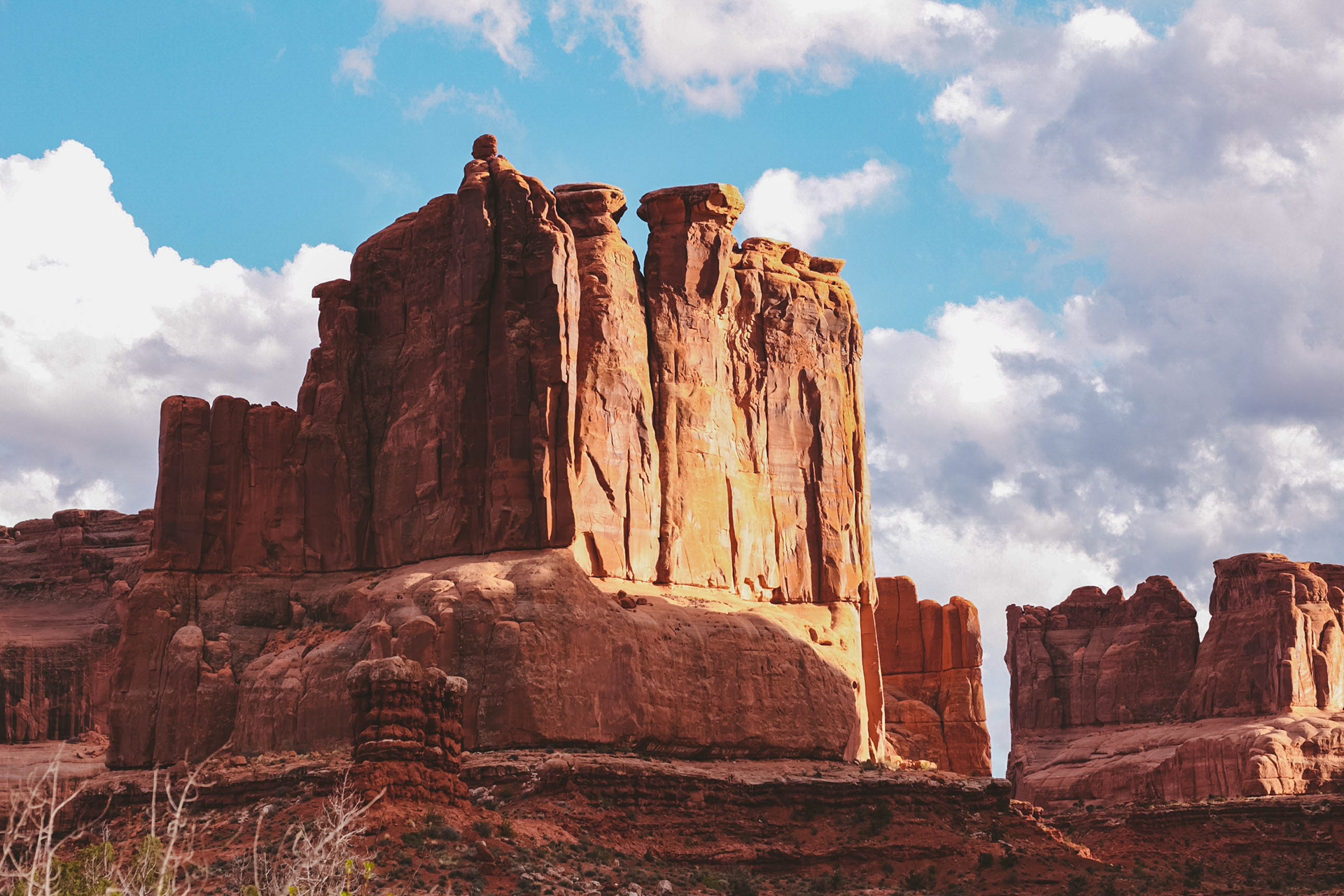 Photograph of a towering rock face along the Park Avenue Trail in Arches National Park, Utah, with massive sandstone cliffs and dramatic desert canyon walls rising above the trail.