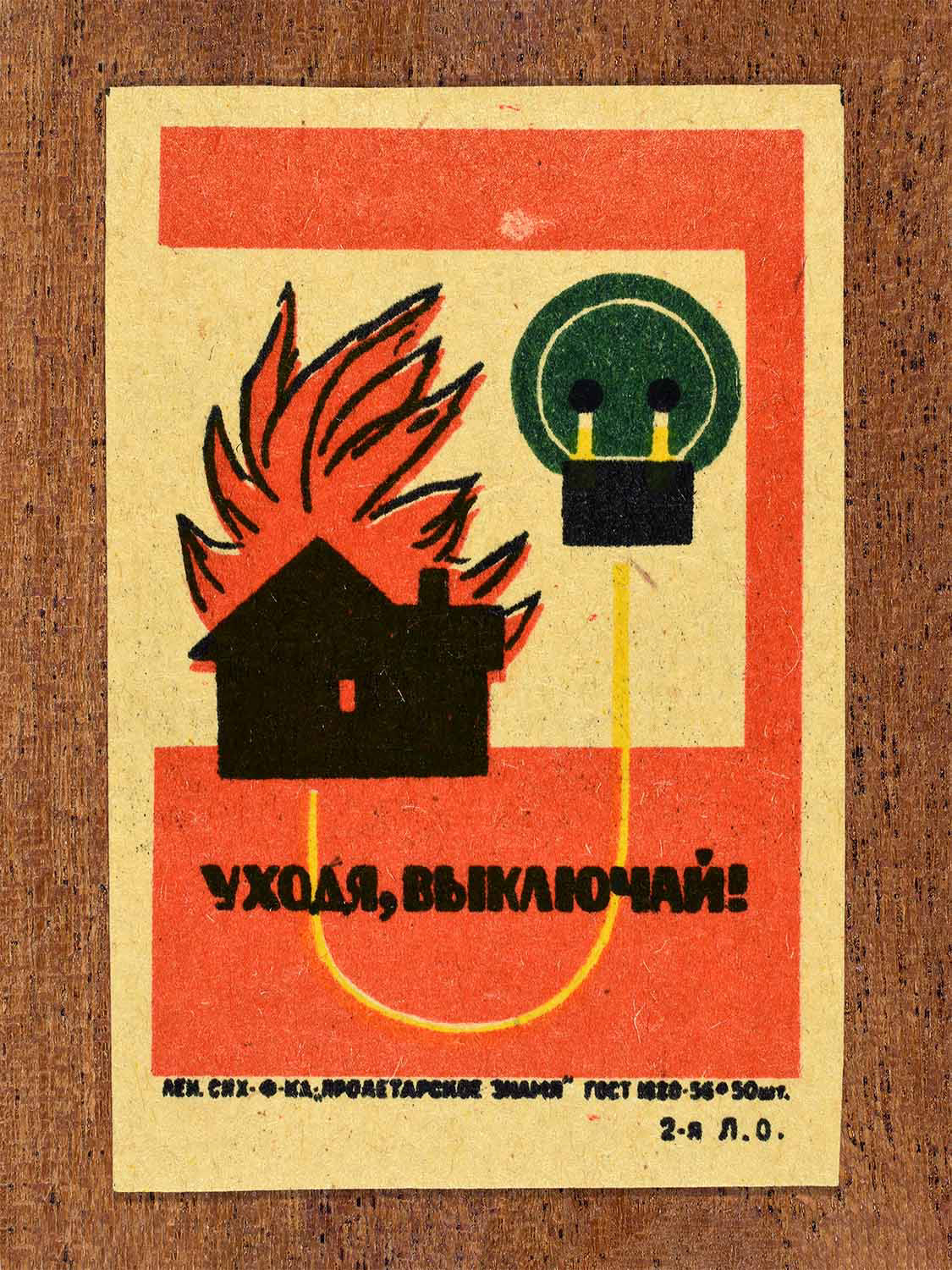 Vintage 1962 Soviet matchbox label showing a burning house and an electric switch. In red, green, yellow and black colours. Produced by the Proletarian Banner match factory to promote switching off electricity when leaving.