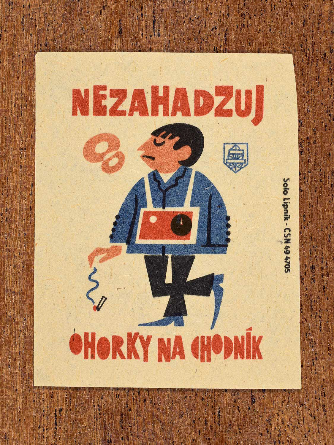 Vintage 1964 Czech matchbox label showing a man dropping a cigarette butt onto a pavement, in blue, red and black colours. Produced by the Solo Lipník match factory to discourage littering cigarette ends in public spaces.