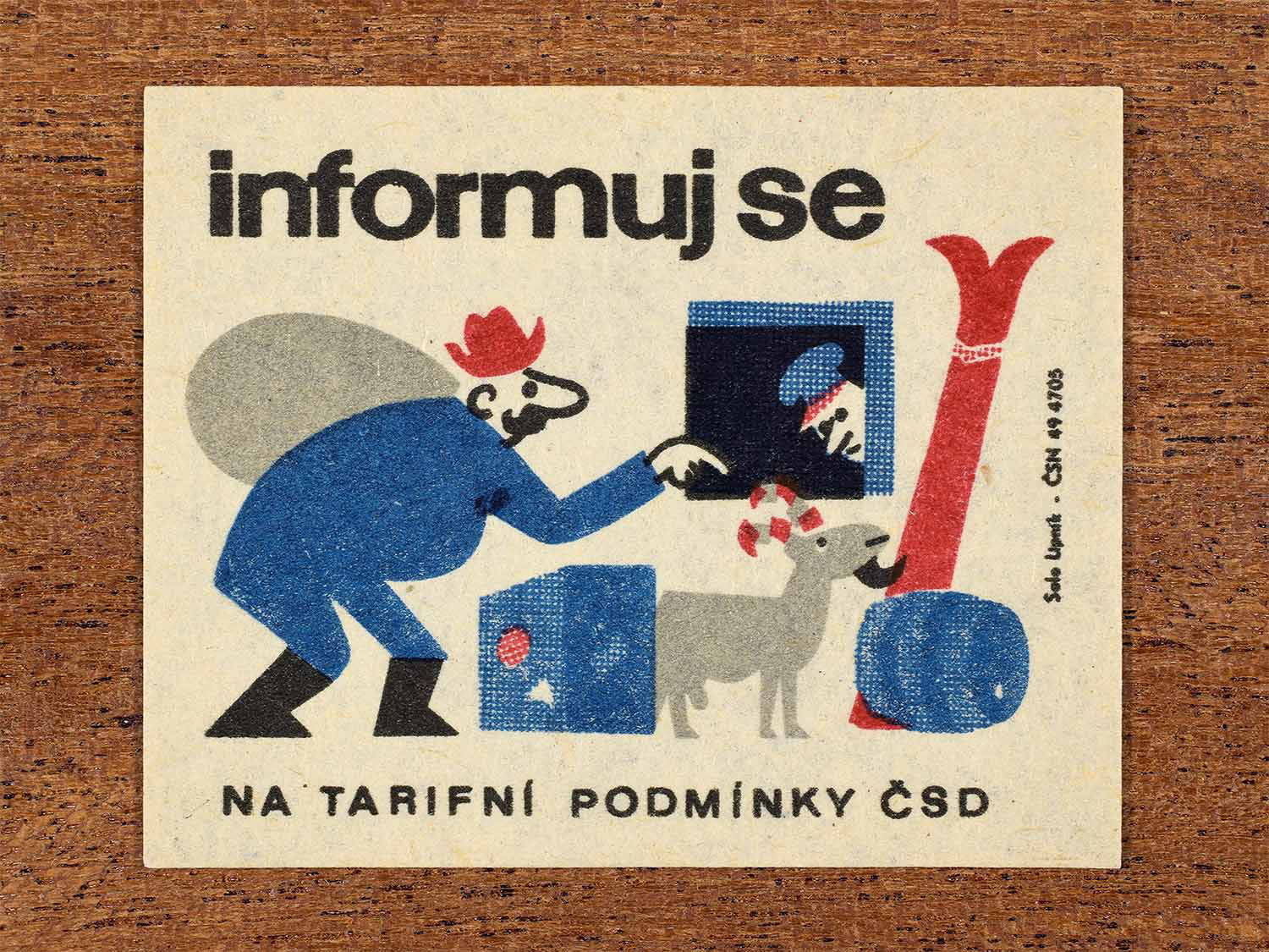 Vintage c. 1964 Czech matchbox label showing a passenger checking luggage with a railway employee, illustrated in blue, red and black. Produced by the Solo Lipník match factory to encourage awareness of ČSD fare conditions.
