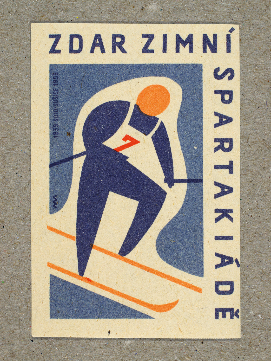 Vintage 1959 Czech matchbox label featuring a stylised figure on skiis leaning forward and going downhill, in blue and red colours. Produced by Solo Lipník & Solo Sušice match factory to promote the nationwide Spartakiad sports programme in Czechoslovakia.