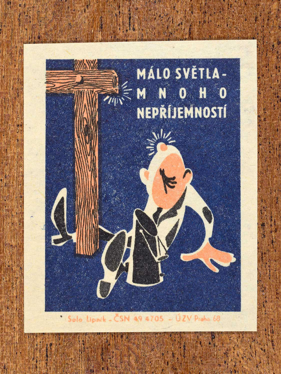 Vintage 1968 Czech matchbox label featuring a cartoon person with a bump on their head sitting next to a wooden post, on blue background. Produced by Solo Lipník match factory to promote proper lighting and maintenance for eye health and safe work practices.