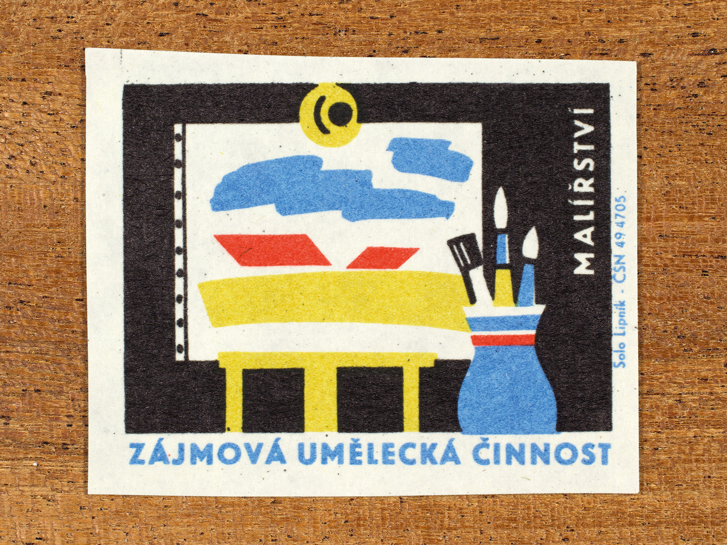Vintage 1969 Czech matchbox label showing a stylised easel, a painted canvas and a pot of brushes, in blue, red, yellow and black colours. Produced by the Solo Lipník match factory to promote state-organised art groups in Czechoslovakia.