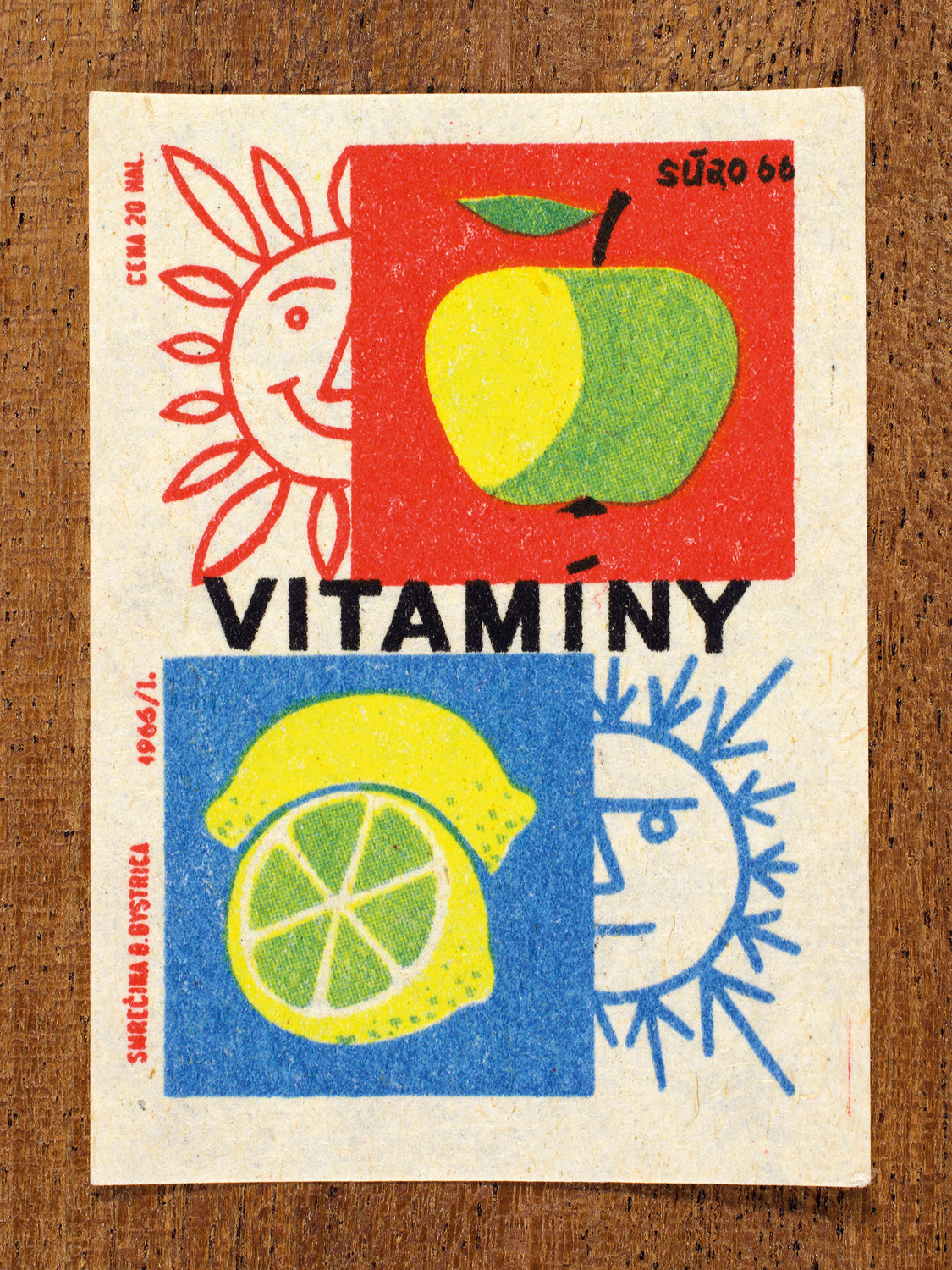 Vintage 1966 Czech matchbox label by Solo Smrečina B. Bystrica featuring an apple on red and and a lemon on blue. It celebrates the sustaining power of vitamins – supporting good health by day and by night.