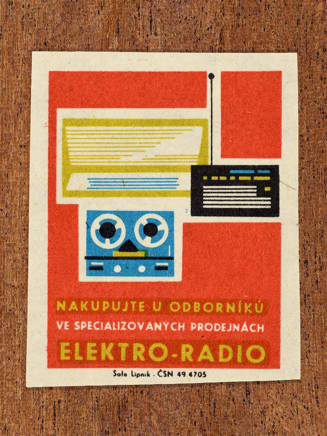 Vintage c. 1967 Czech matchbox label showing a reel-to-reel tape recorder and radio equipment in red, blue, yellow and black colours. Produced by the Solo Lipník match factory to promote shopping for electrical and radio products in specialised retail stores.