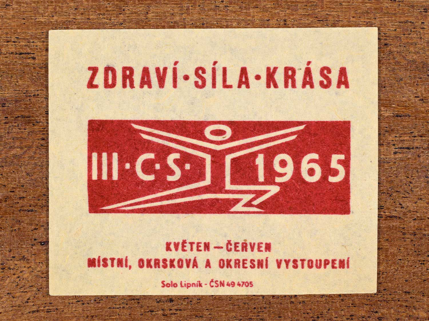 Vintage 1965 Czechoslovak matchbox label showing a symbolic athletic figure in red. Produced by the Solo Lipník match factory to promote physical fitness and sporting achievement.