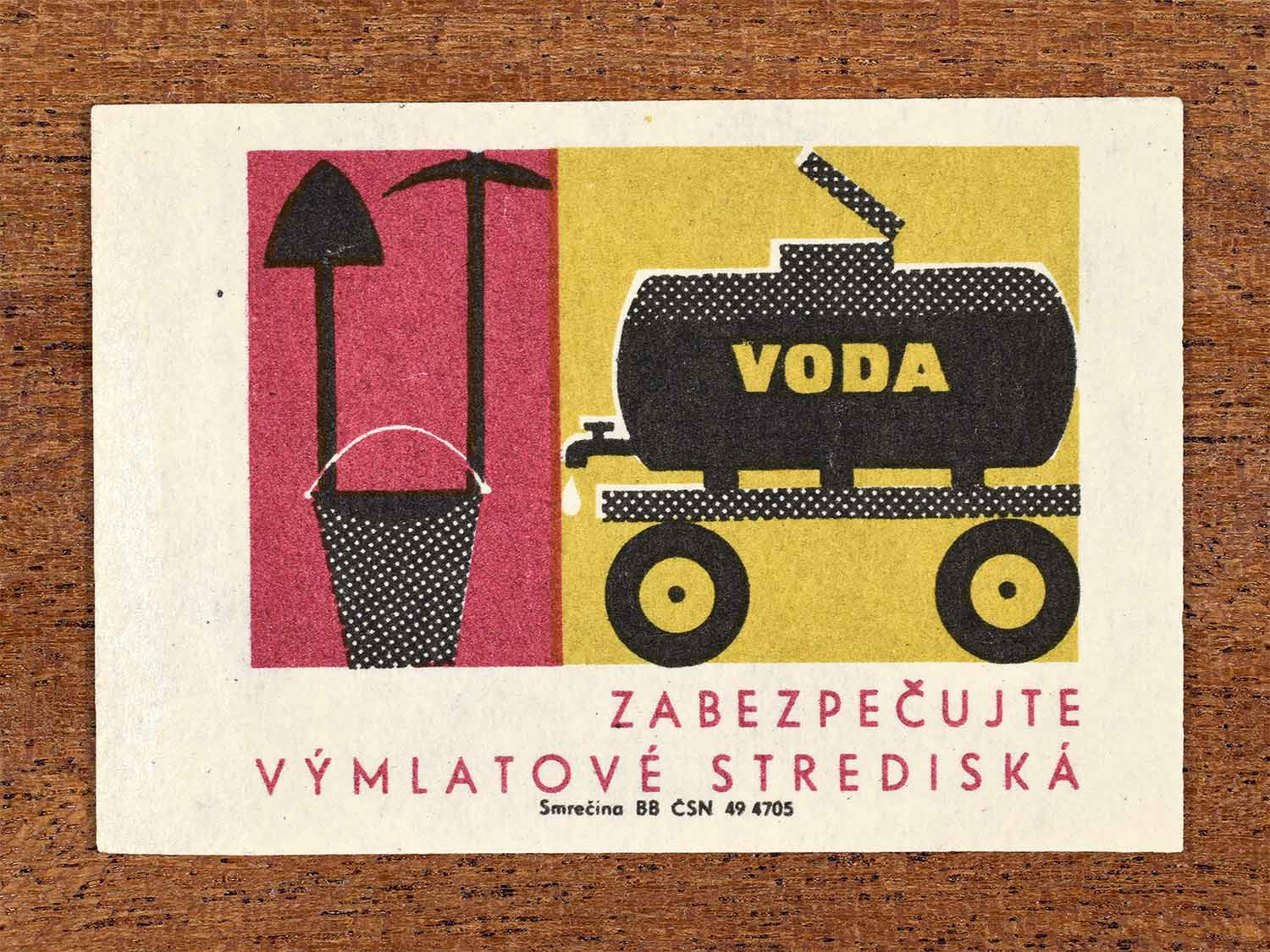 Vintage 1964 Czechoslovak matchbox label showing a mobile water tank and firefighting equipment beside agricultural tools, in yellow, black and red. Produced by the Smrečina match factory to promote fire-safety protection at grain-threshing centres.