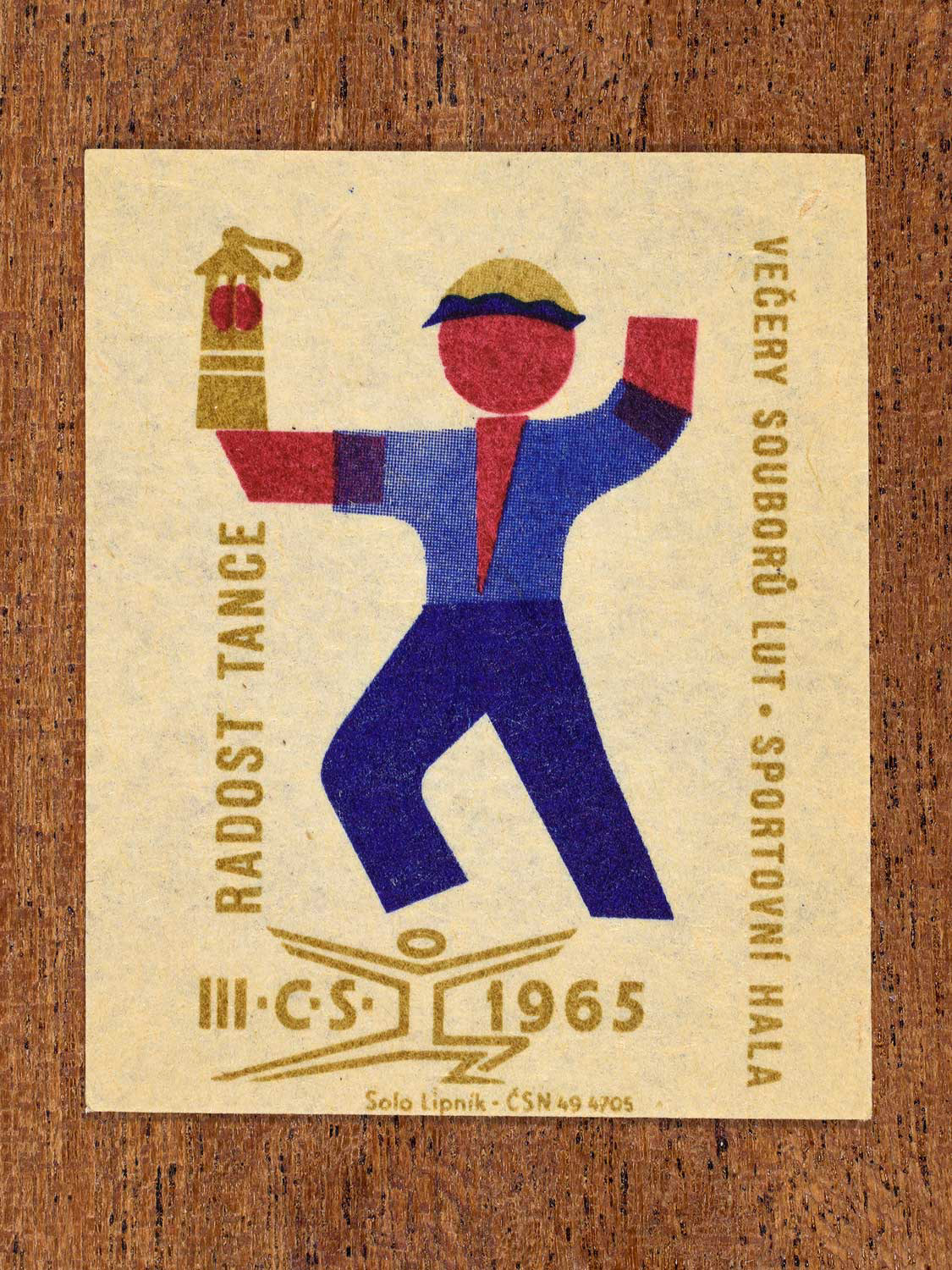 Vintage 1965 Czechoslovak matchbox label showing a stylised folk dancer in blue, red and gold colours. Produced by the Solo Lipník match factory to promote joyful social dance.