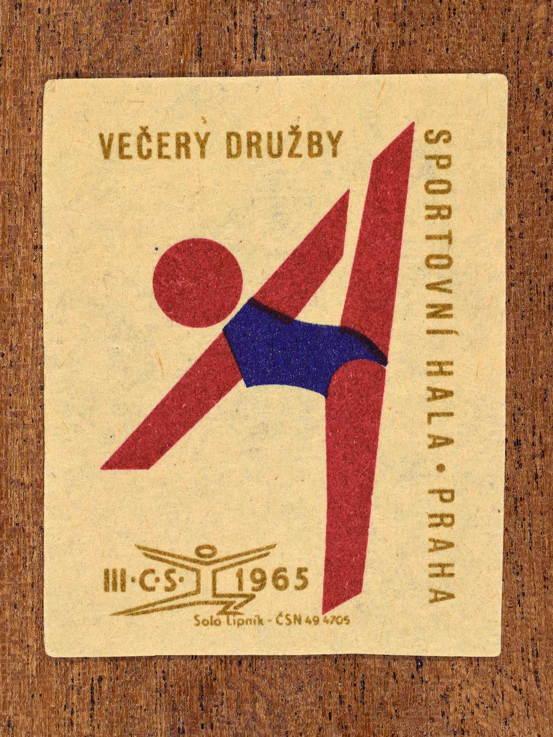 Vintage 1965 Czechoslovak matchbox label showing an abstract athlete figure, in blue, red and gold colours. Produced by the Solo Lipník match factory to promote physical fitness and sporting achievement.