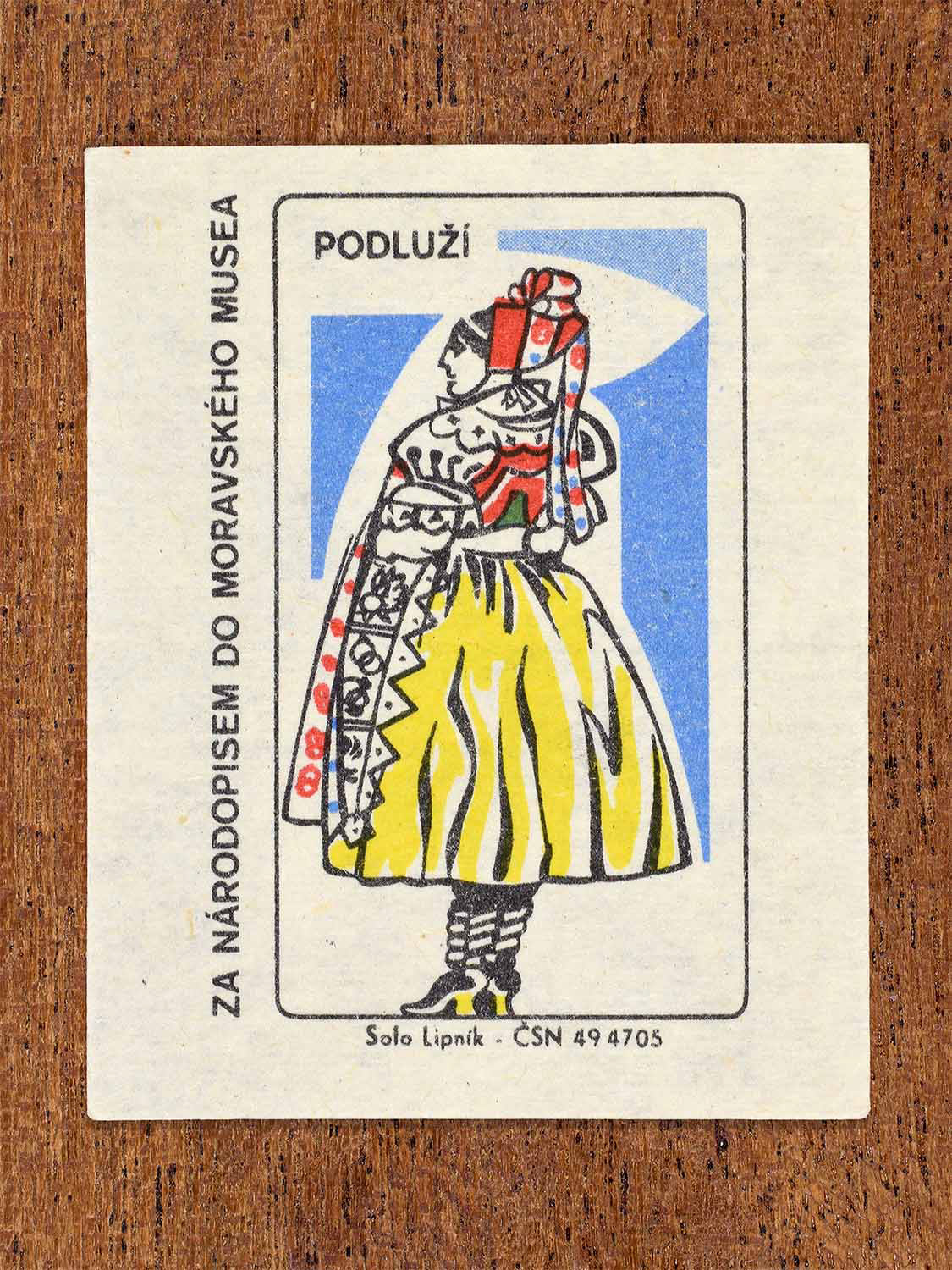 Vintage c. 1968 Czech matchbox label showing a female folk costume from the Podluží region with patterned skirt and headscarf. Produced by the Solo Lipník match factory to promote Moravian folk culture through the Moravian Museum.