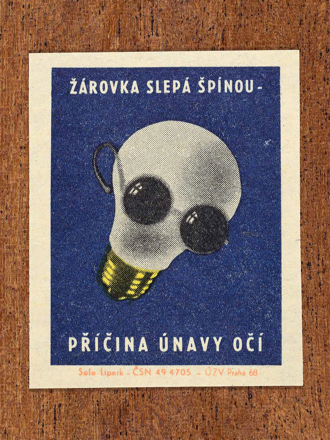 Vintage 1968 Czech matchbox label featuring a light bulb wearing sunglasses, on blue background. Produced by Solo Lipník match factory to promote proper lighting and maintenance for eye health and safe work practices.