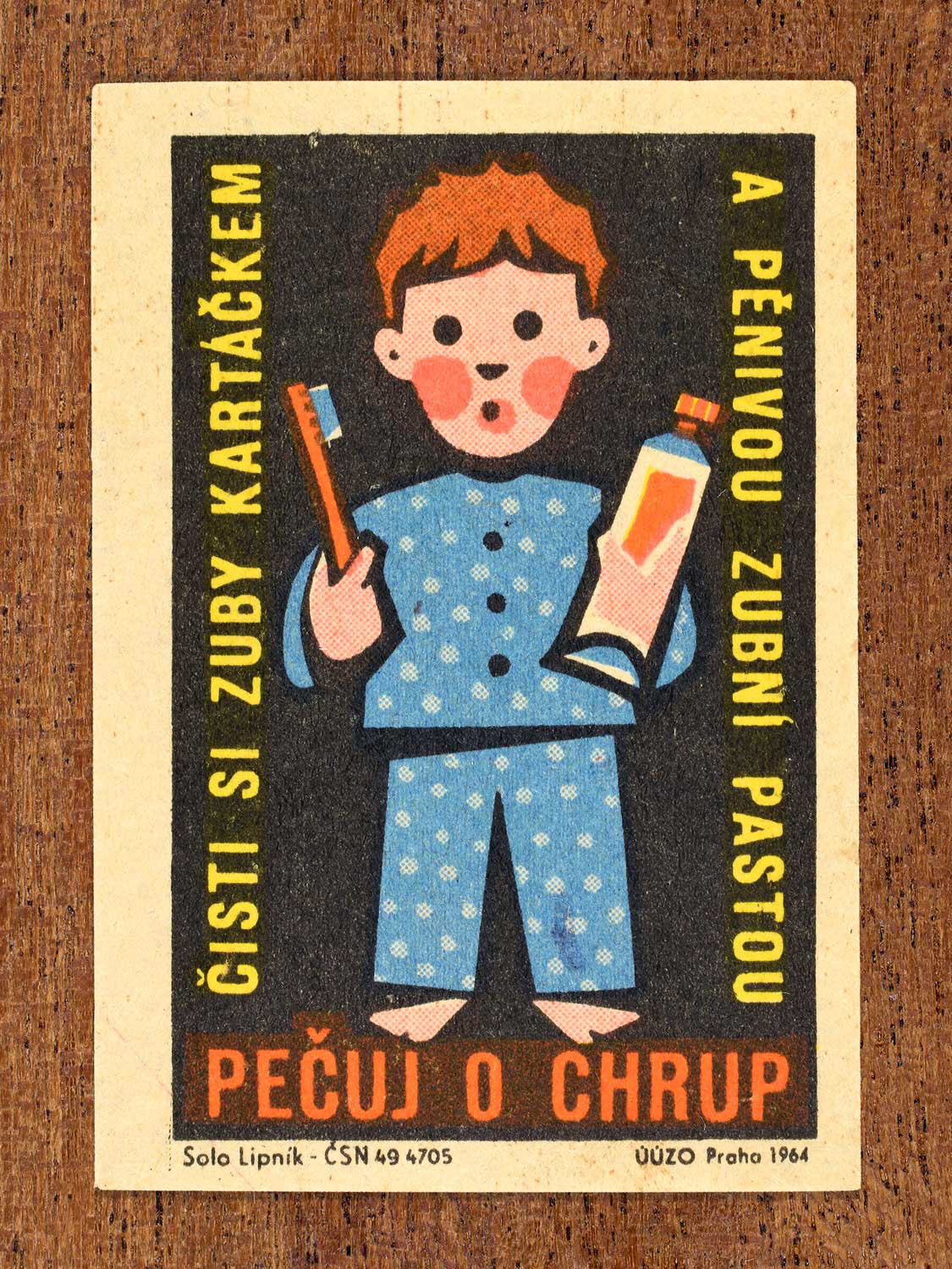 Vintage 1964 Czech matchbox label showing an illustrated child in pyjamas holding a toothbrush and toothpaste, on a black background. Produced by the Solo Lipník match factory to promote nutrition advice and hygiene habits in protecting healthy teeth.