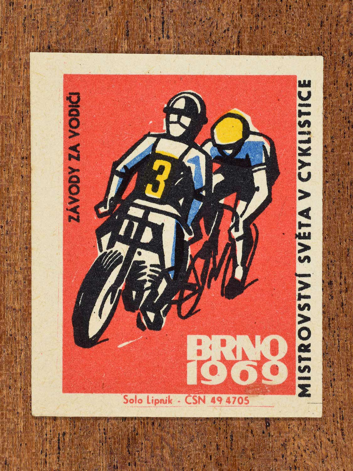 Vintage 1969 Czech matchbox label showing a stylised cyclist racing behind a pacer, on a red background. Produced by the Solo Lipník match factory to promote paced racing at a cycling championship in Brno, Czechoslovakia.