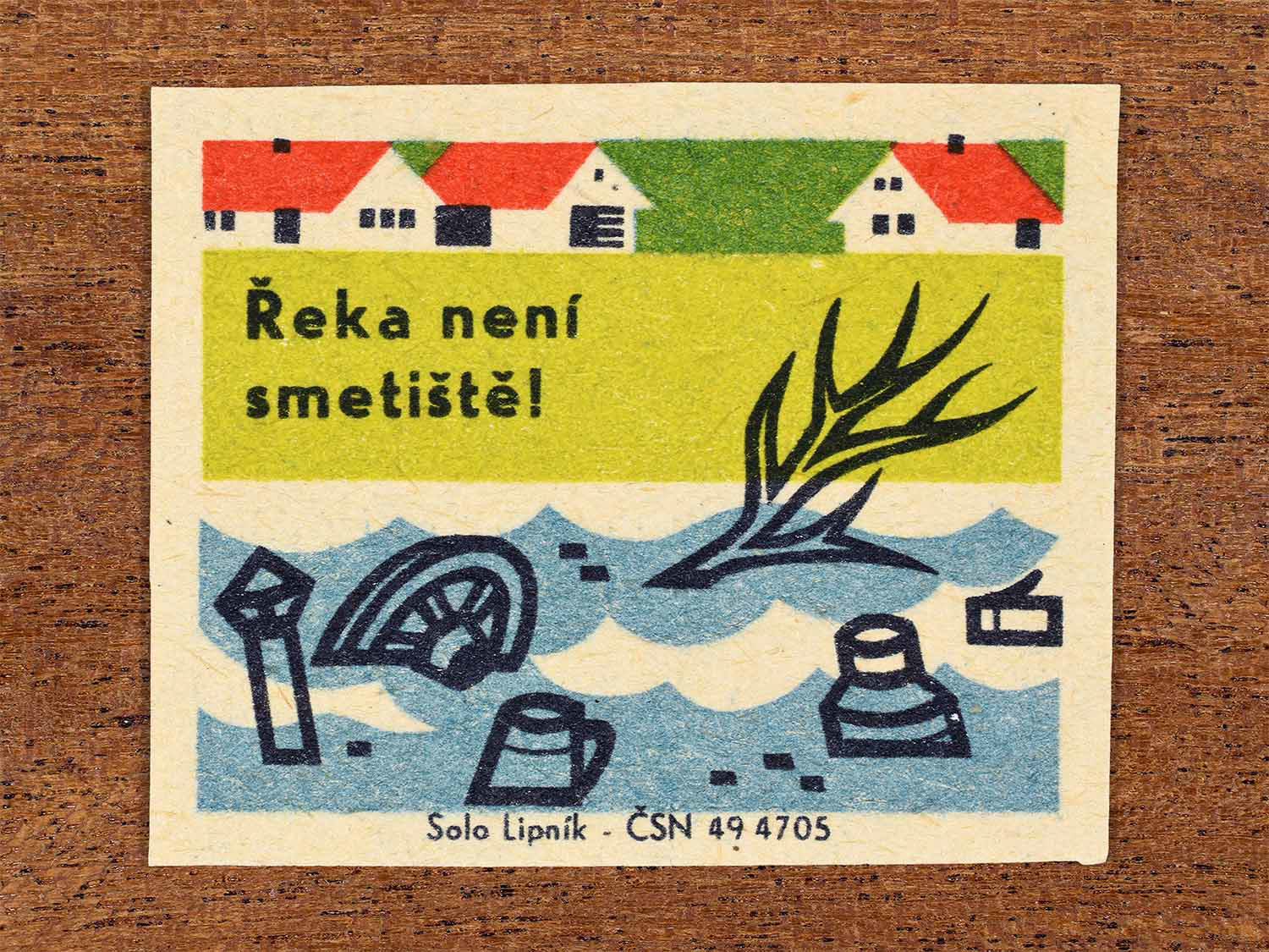 Vintage 1966 Czech matchbox label showing household waste thrown into water near riverside houses in green, blue and red colours. Produced by the Solo Lipník match factory to warn that rivers are not rubbish dumps.
