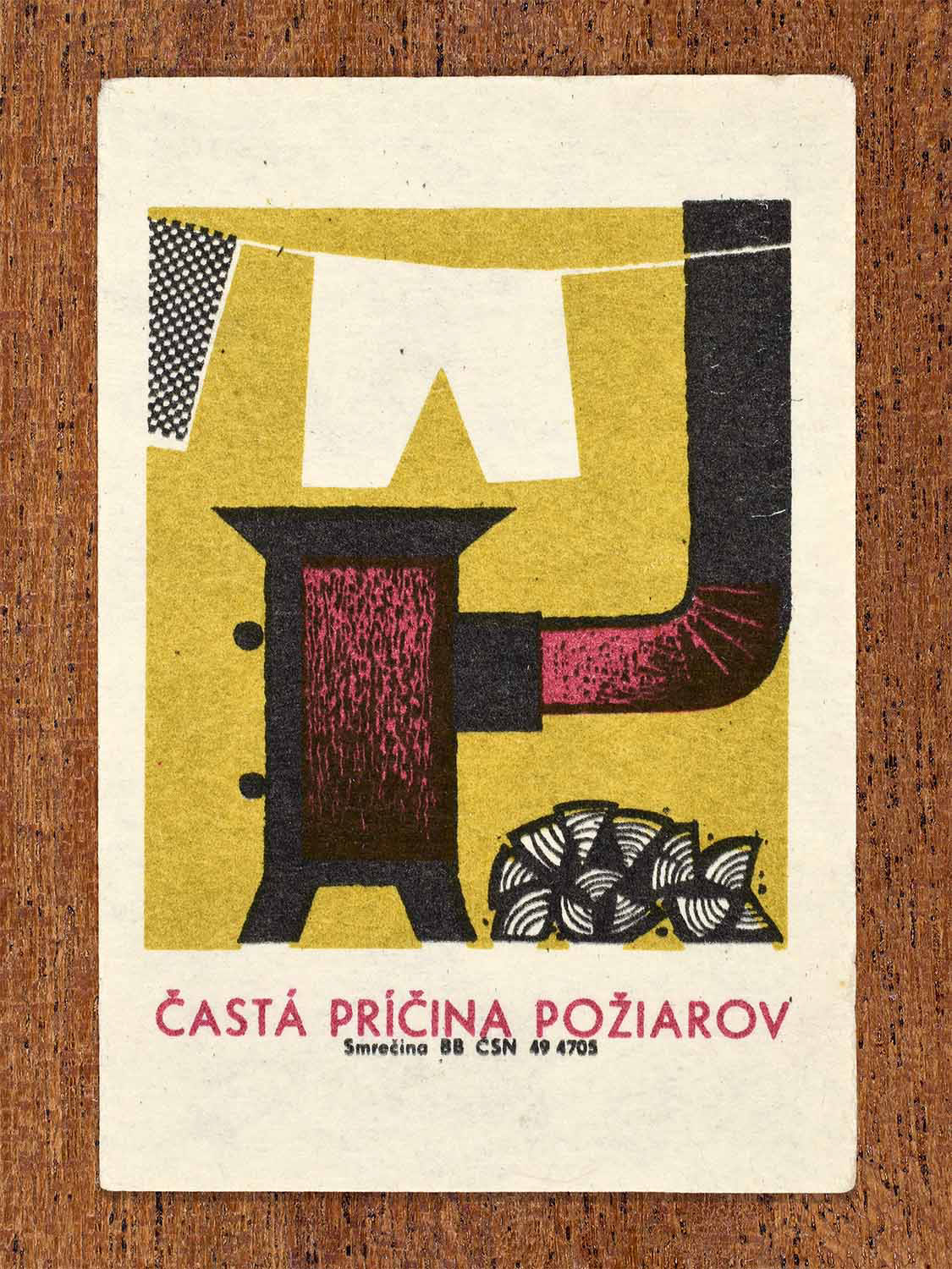 Vintage 1964 Czechoslovak matchbox label showing a stylised stove with laundry hanging above, in yellow, black and red. Produced by the Smrečina match factory to show the dangers of hanging laundry near cooking appliances.