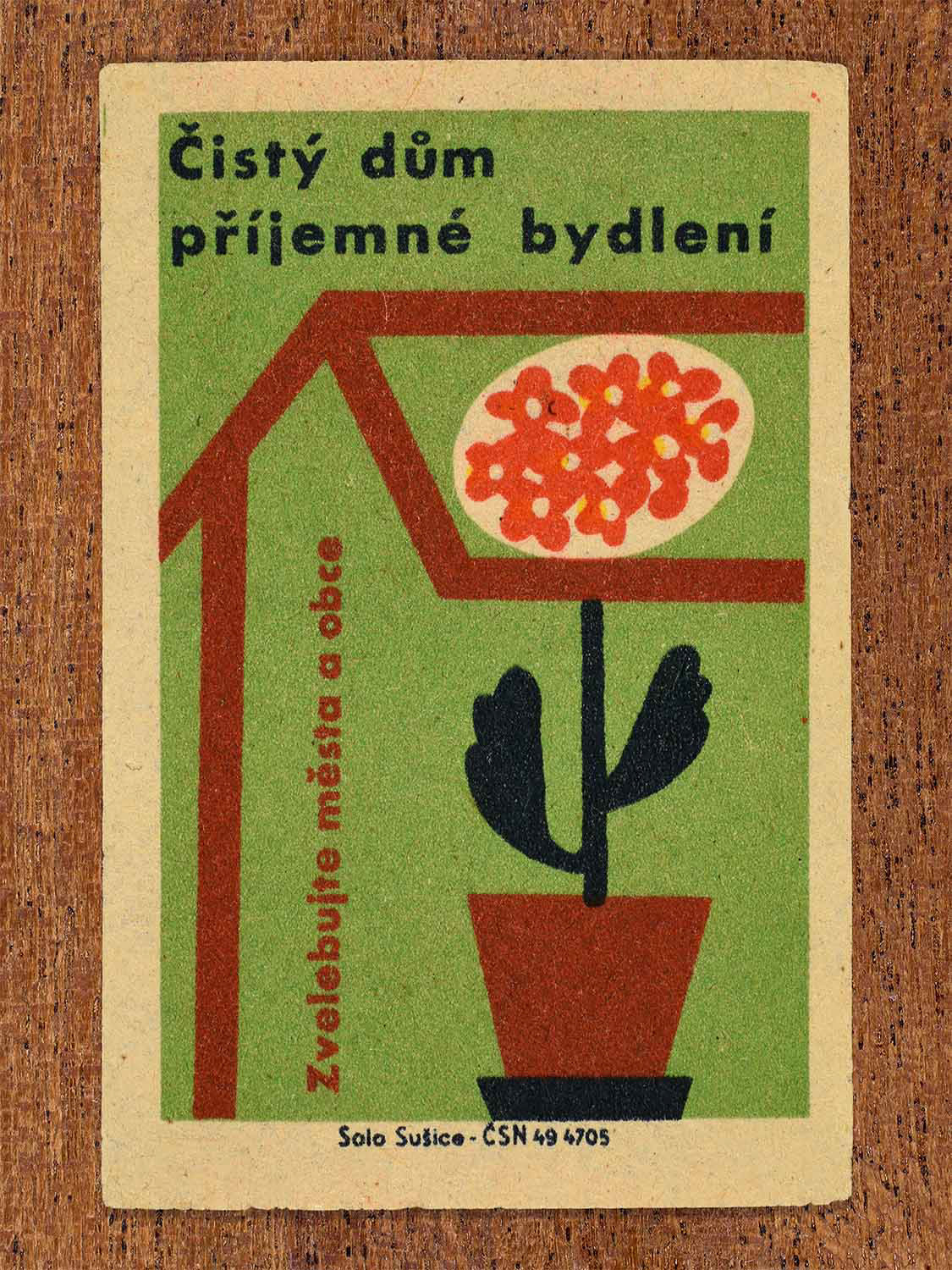 Vintage 1961 Czech matchbox label showing the outline of a house enclosing a potted blooming geranium plant. Produced by the Solo Sušice match factory to promote clean homes and pleasant domestic environments.