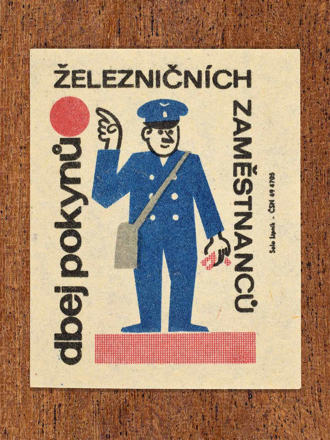 Vintage c. 1964 Czech matchbox label showing a railway employee giving instructions, illustrated in blue, red and black. Produced by the Solo Lipník match factory to encourage obedience to railway staff instructions.