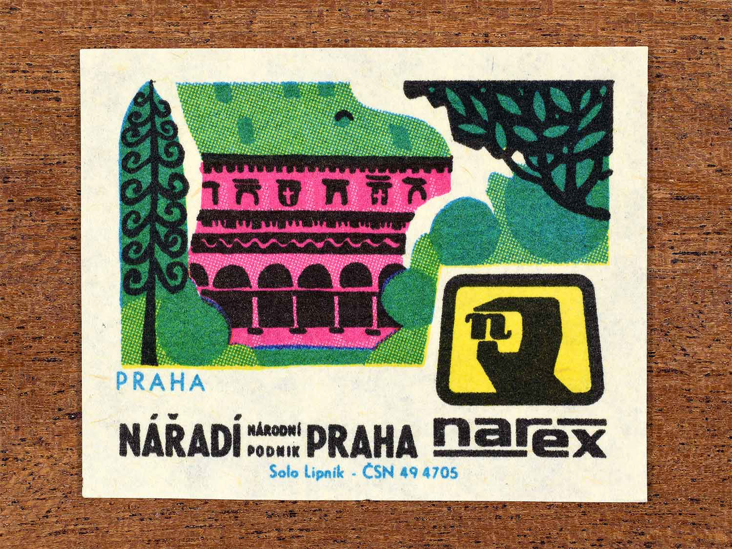 Vintage 1967 Czech matchbox label showing a historic Prague building framed by trees in bright green and pink. Produced by the Solo Lipník match factory to promote Prague and Narex, the national tool enterprise in Czechoslovakia.