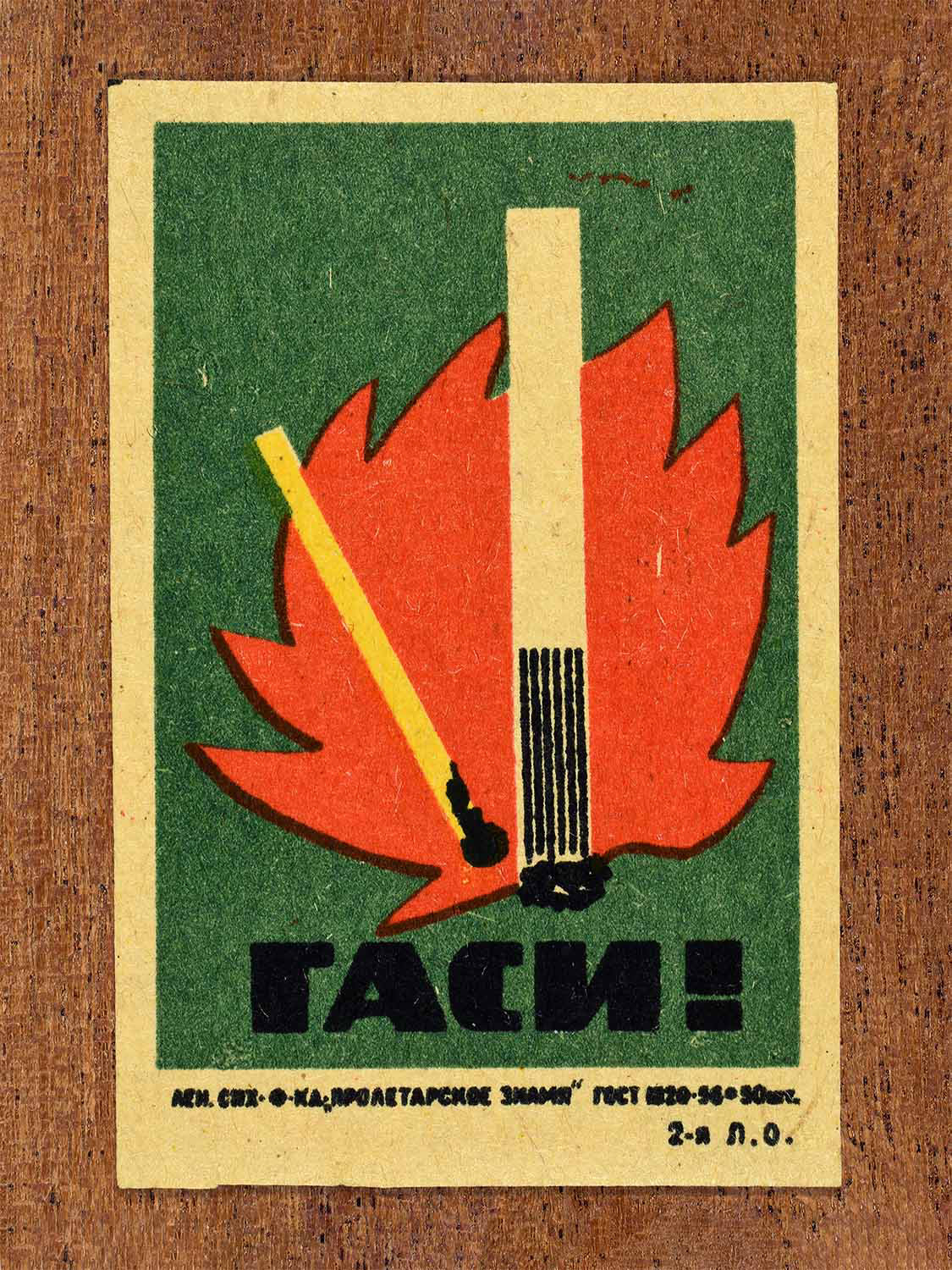Vintage 1962 Soviet matchbox label showing an extinguished match and cigarette. In green, red, yellow and black colours. Produced by the Proletarian Banner match factory to promote fire prevention awareness.