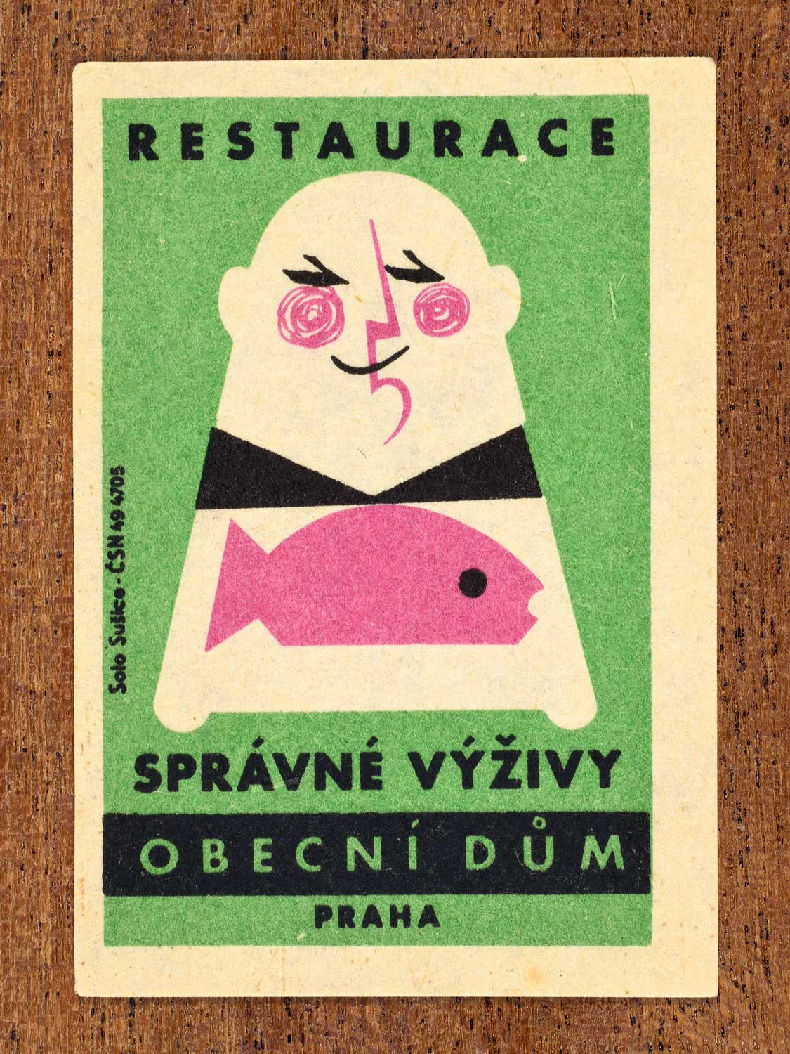 Vintage 1964 Czech matchbox label showing a stylised diner holding a fish on a green background. Produced by the Solo Sušice match factory to promote a restaurant inside Prague's Obecní dům (Municipal House) in Czechoslovakia.
