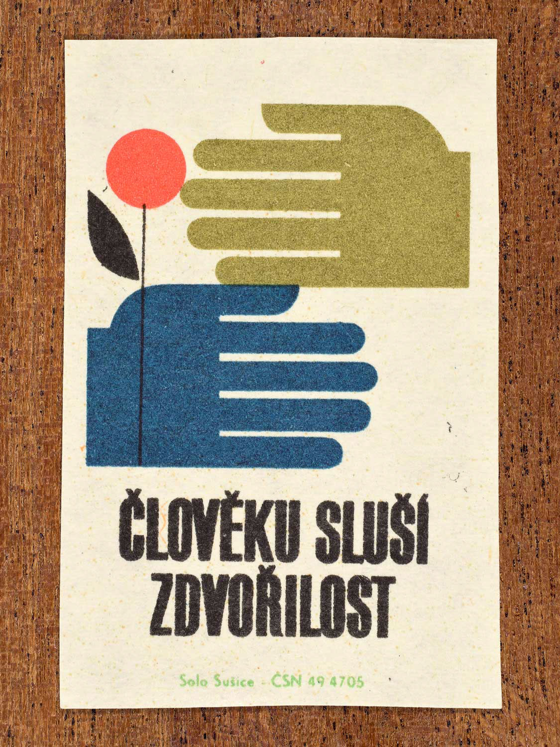 Vintage c. 1966 Czech matchbox label showing a stylised flower and two hands interacting in a gesture of courtesy. Produced by the Solo Sušice match factory to promote politeness, respect, and considerate social conduct.