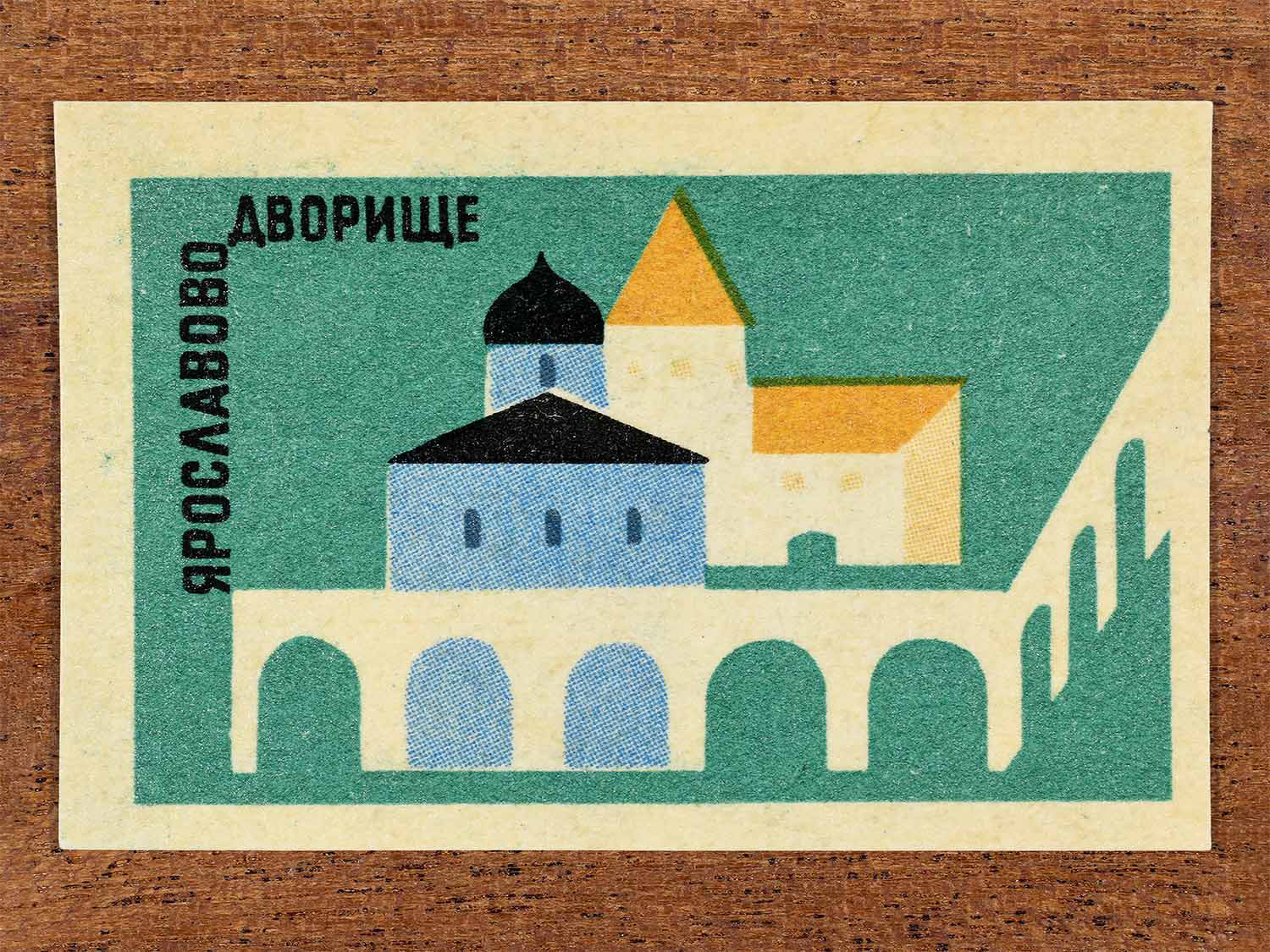 Vintage 1966 Soviet matchbox label showing a geometric illustration of Yaroslavovo Dvorishche (Yaroslav’s Court) in Novgorod. Produced by a Soviet match factory to commemorate historic Russian architecture.