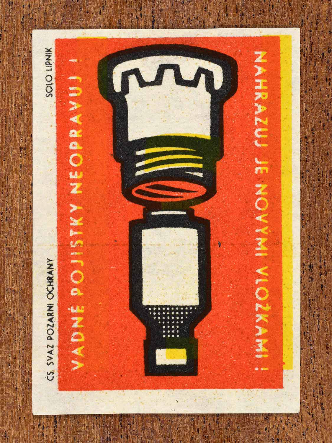 Vintage 1963 Czech matchbox label showing a fuse cartridge in red, black and yellow colours. Produced by the Solo Lipník match factory to encourage replacing faulty fuses instead of repairing them.
