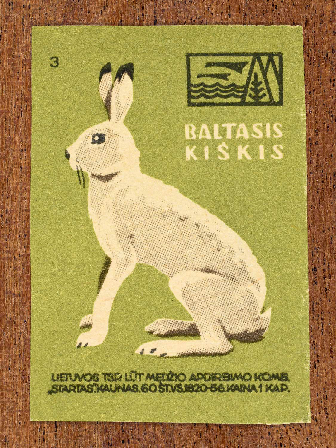 Vintage 1959 Lithuanian matchbox label showing a stylised white winter hare sitting upright, on green background. Produced by the LŪT Wood Processing Combine “Startas” in Kaunas to familiarise citizens with local wildlife.